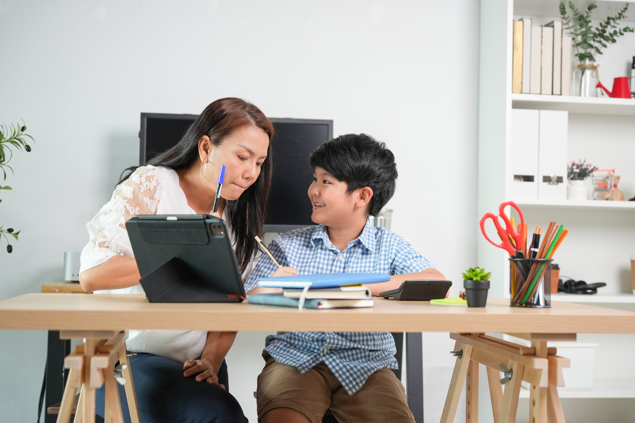 Asian Mother Tutoring Son at Home, Tutor Helping Young Boy with Homework in Living Room