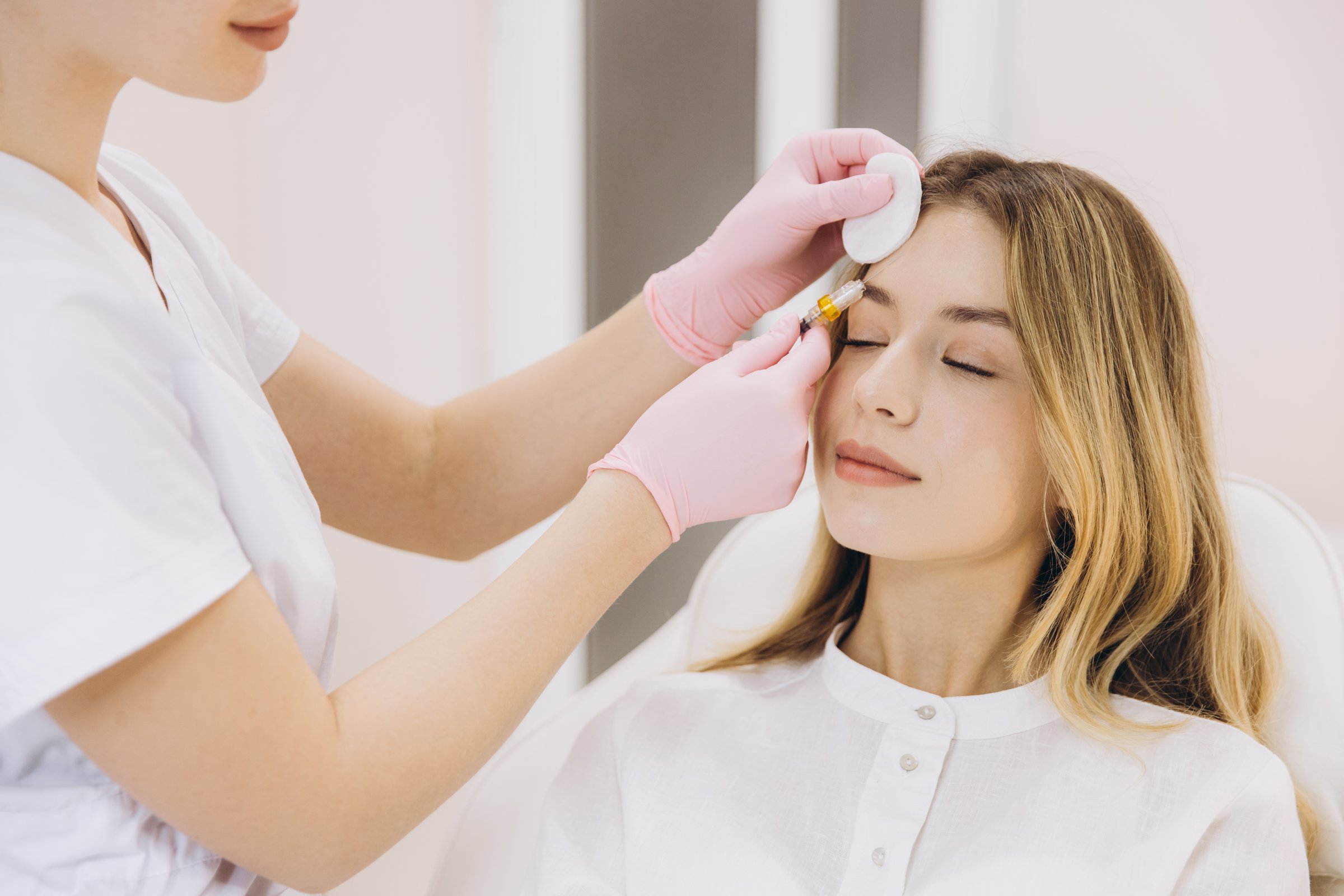 Professional cosmetologist administering facial rejuvenation injection, treating patient with precision in modern medical aesthetic setting