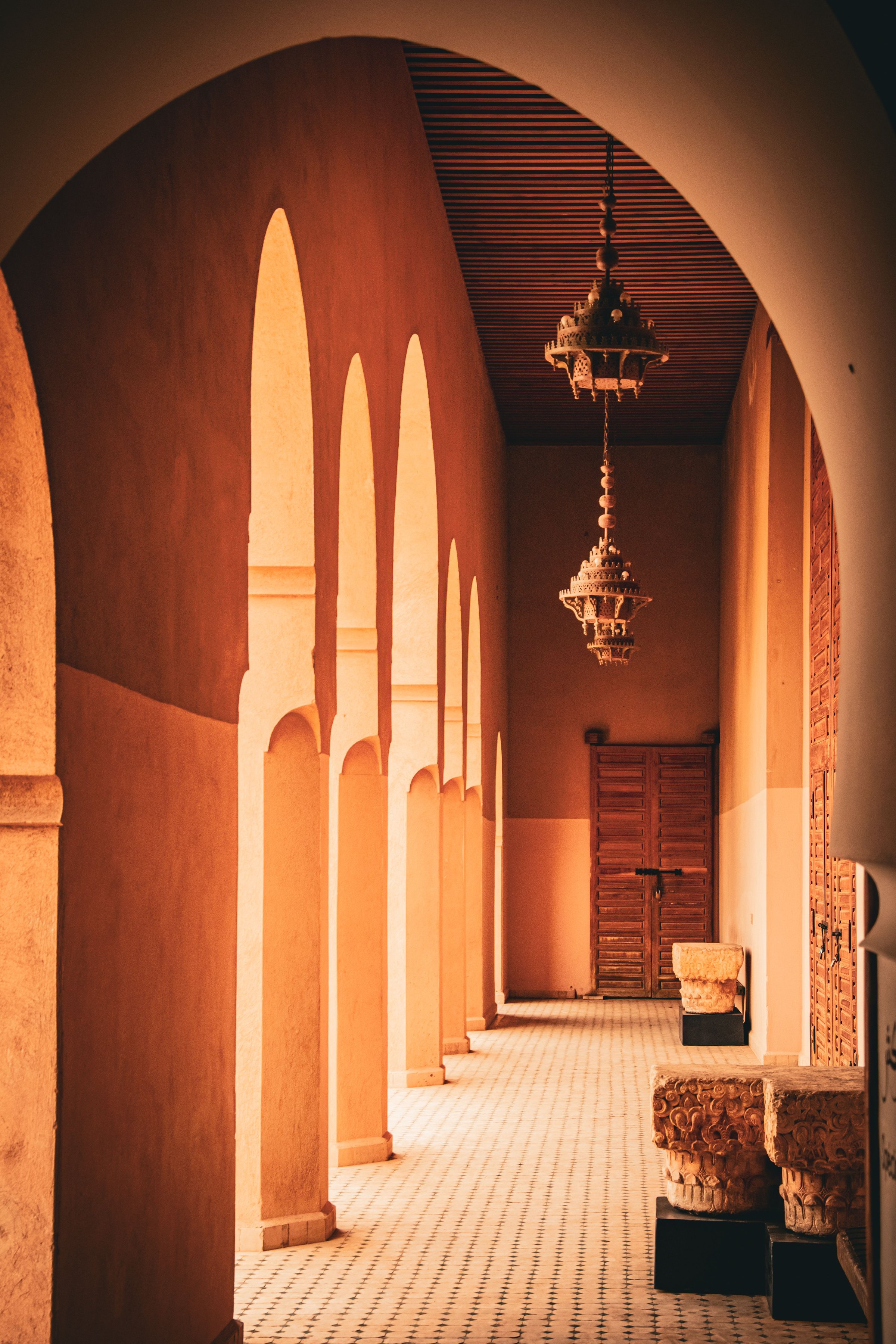 A beautifully lit corridor with arches and hanging lanterns in a Moroccan building in Marrakech