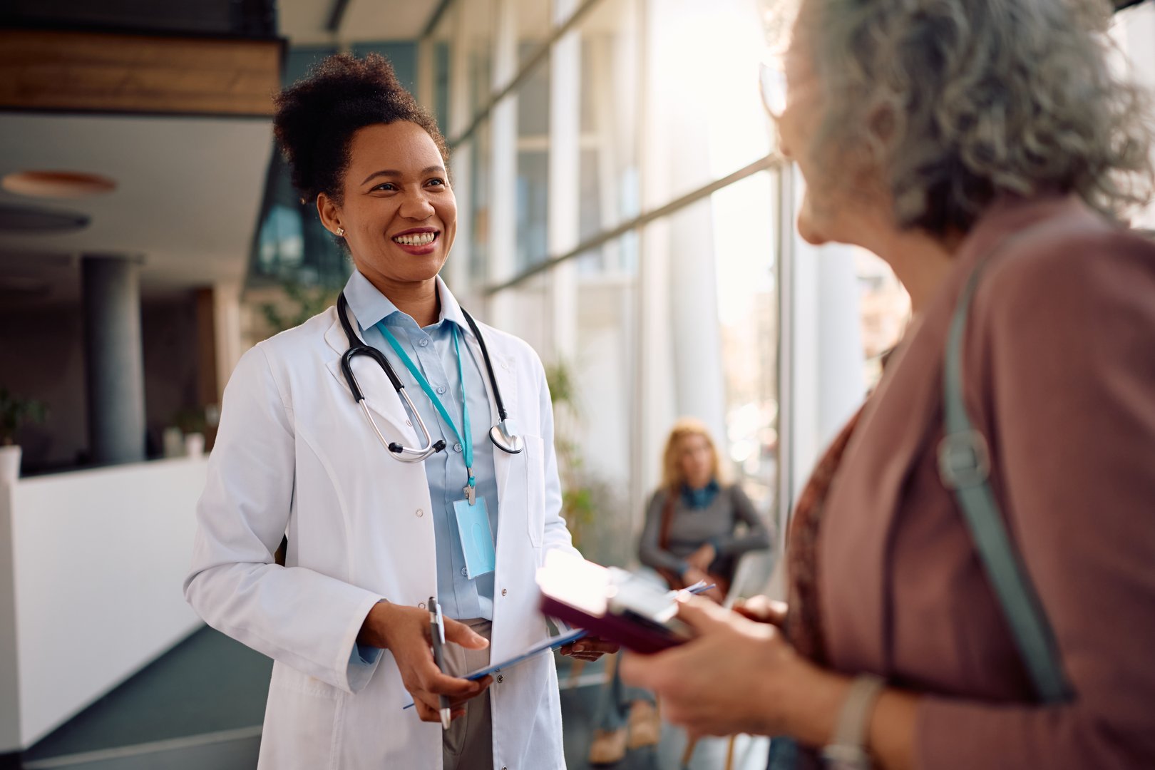 Happy African American doctor and her senior patient communicating during medical appointment at clinic.