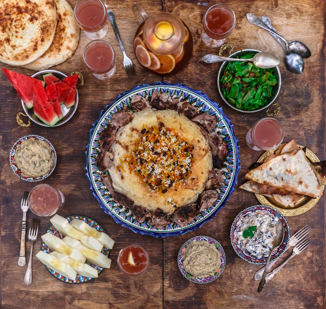 Pilaf with lamb in traditional plate with appetizers, top view flat lay.