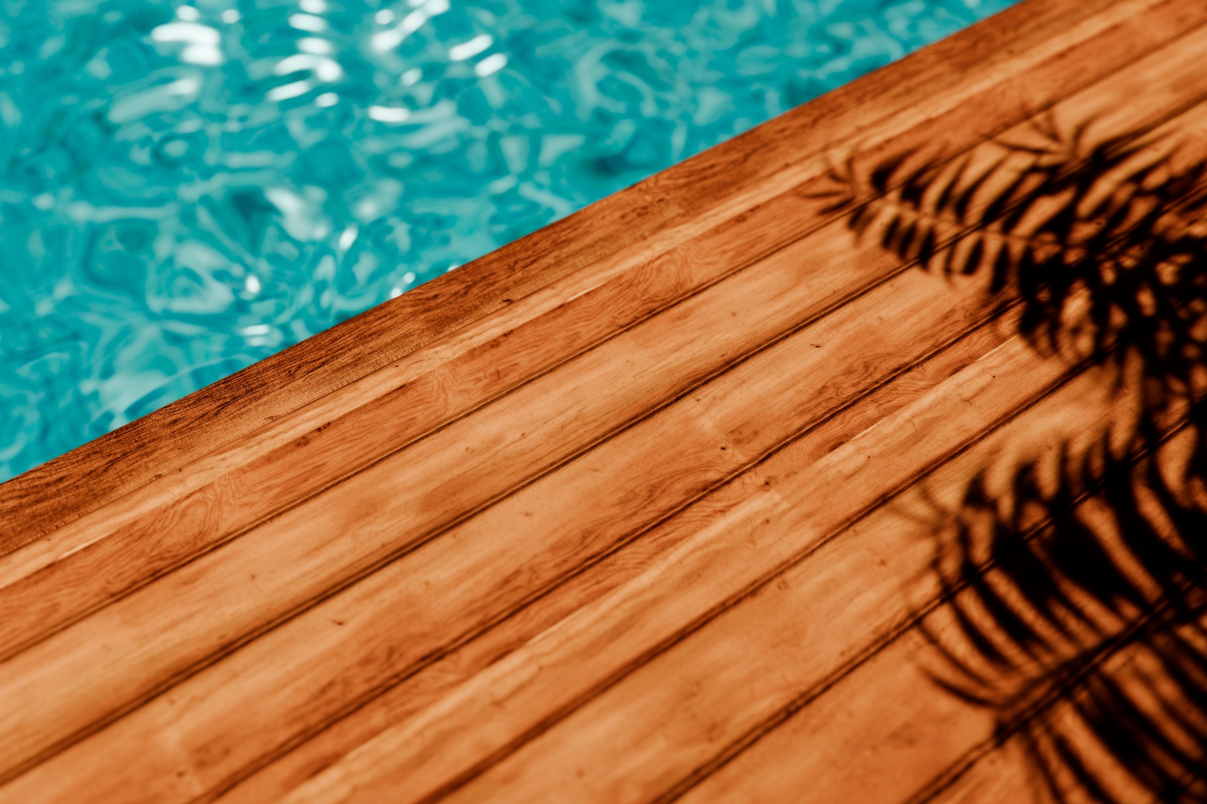 Top view of wooden decking floor with palm shadow behind luxury swimming pool. Summer holiday background. Poolside podium table for spa, beauty, cosmetic and skincare product placement mockup from above.