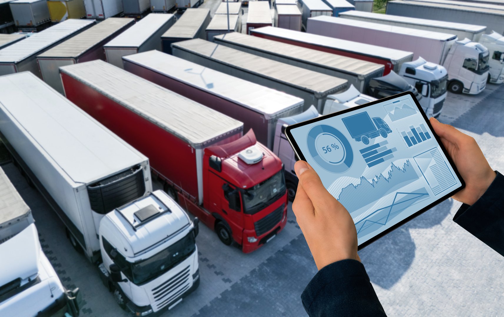 Close up of male hands of manager with a digital tablet on the background of trucks. Fleet management