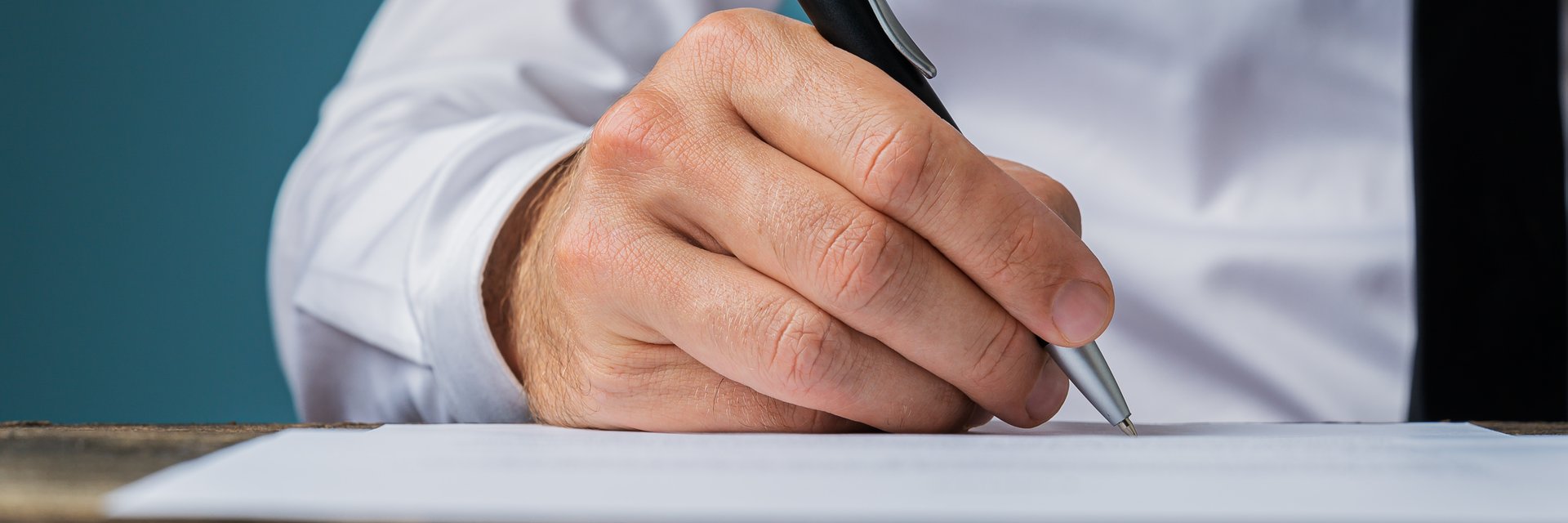 Wide view image of businessman signing a document or contract.