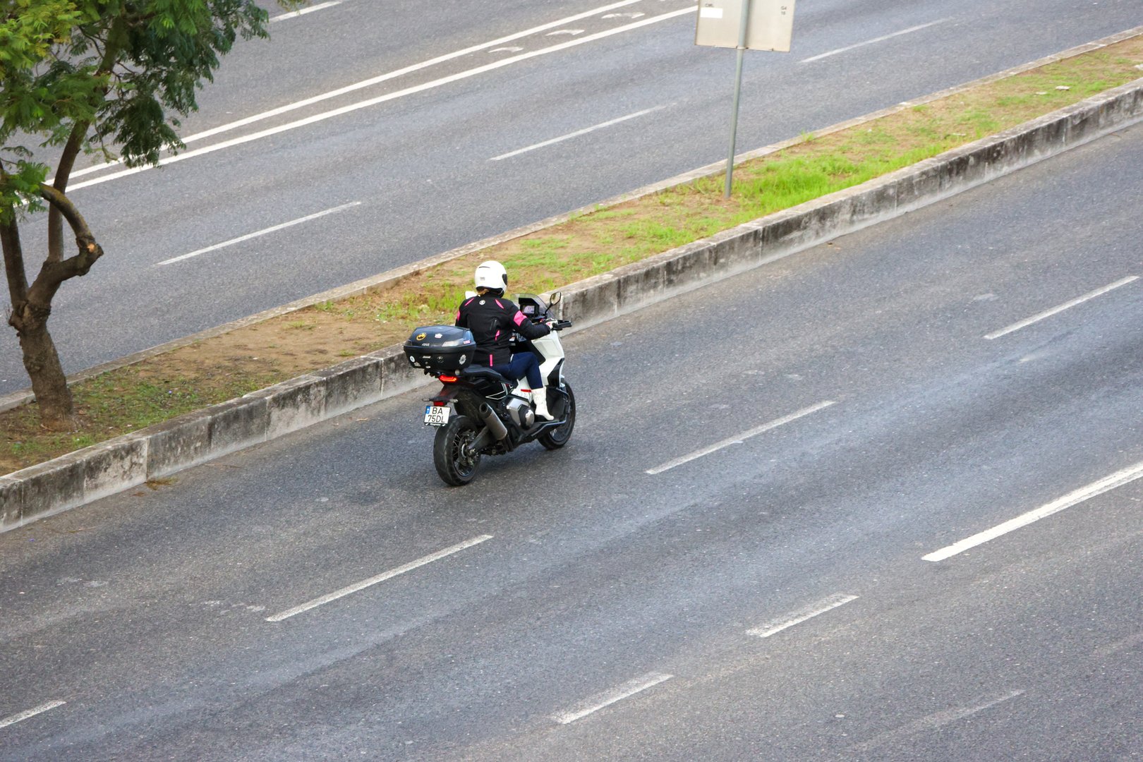 Motorcyclist wearing helmet riding scooter on city highway during daytime