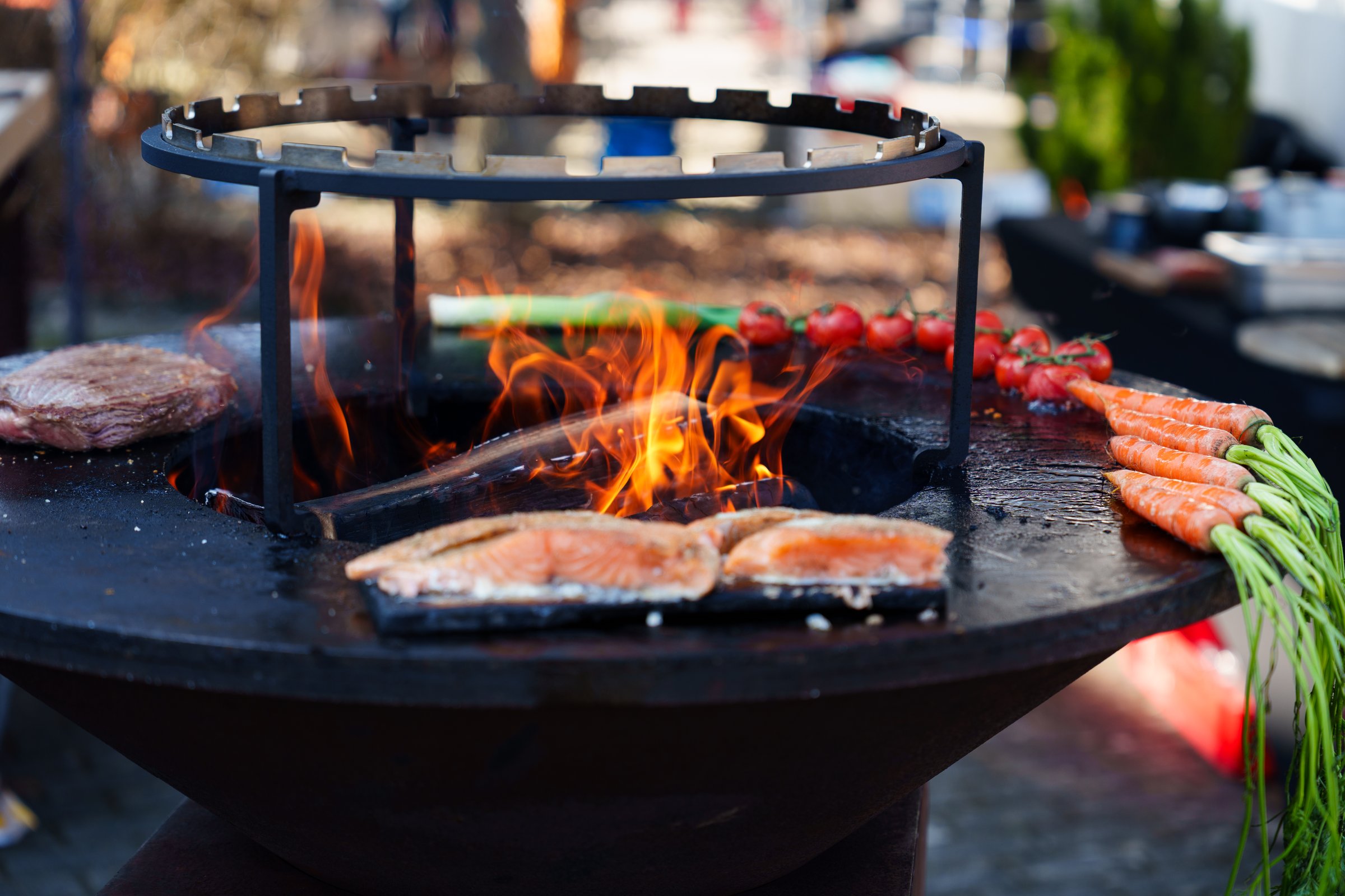 Grilled meat and fresh vegetables cooking on an outdoor barbecue grill with flames in the background. Perfect for BBQ party and food concepts.