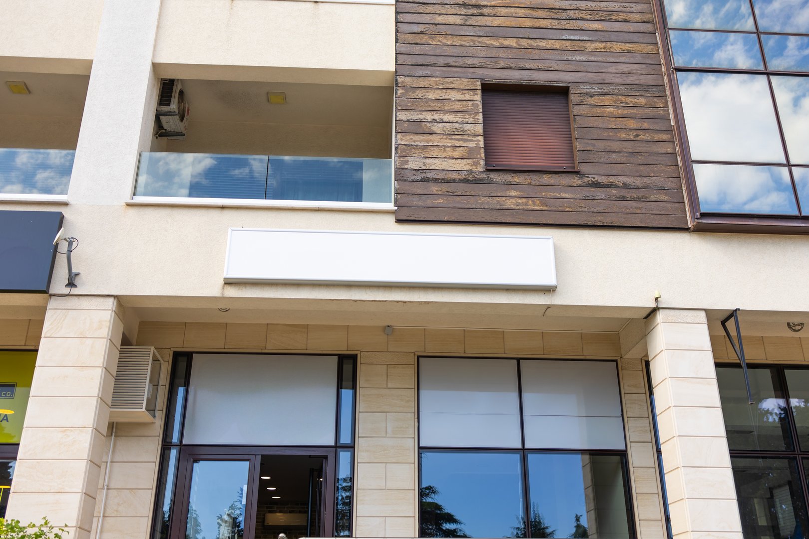 Blank shop sign above modern building entrance, copy space. Branding concept, urban retail and commercial storefront exterior