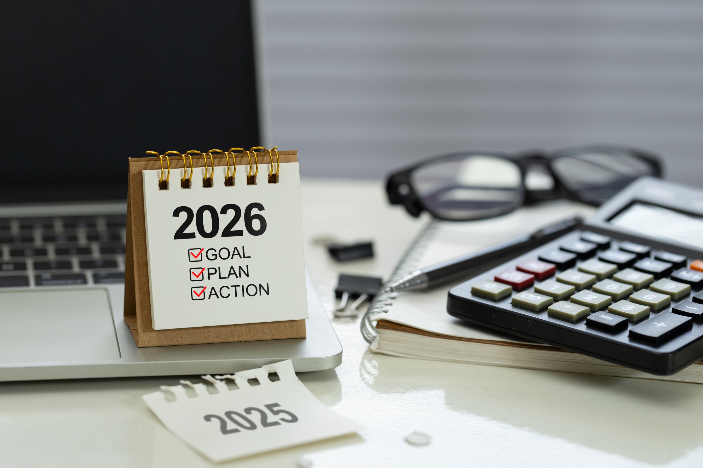 Desk calendar 2026 with checklist Goal, Plan, Action on office workspace beside calculator, notebook, pen and laptop, represent financial planning, budget, KPI targets and execution for the new year