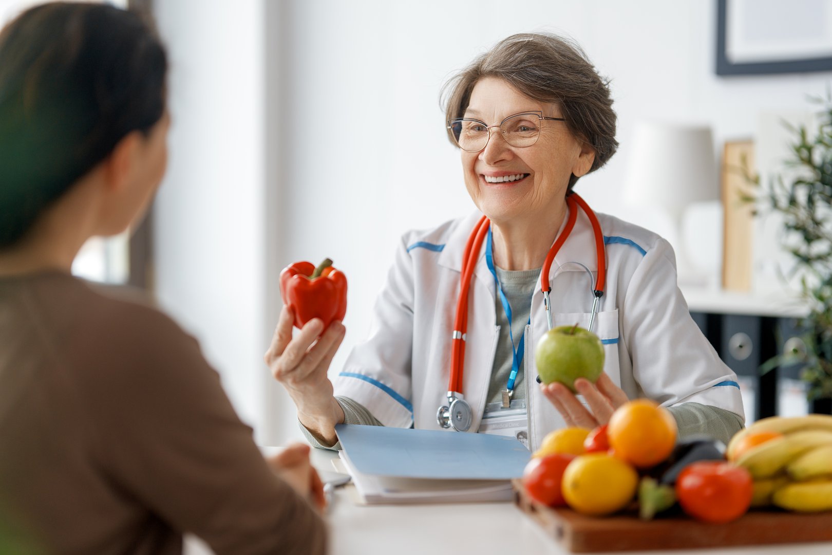 Happy doctor is working in medicine office. A woman is talking to a patient about the importance of eating fruits and vegetables.
