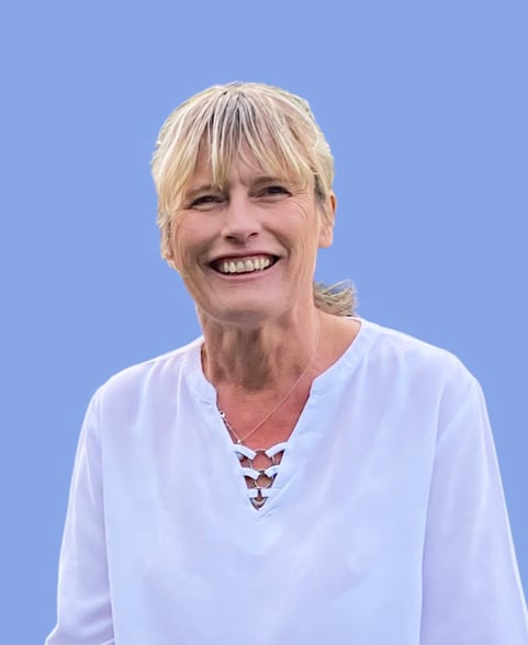 Smiling woman with blonde hair in a white blouse, set against a solid blue background.