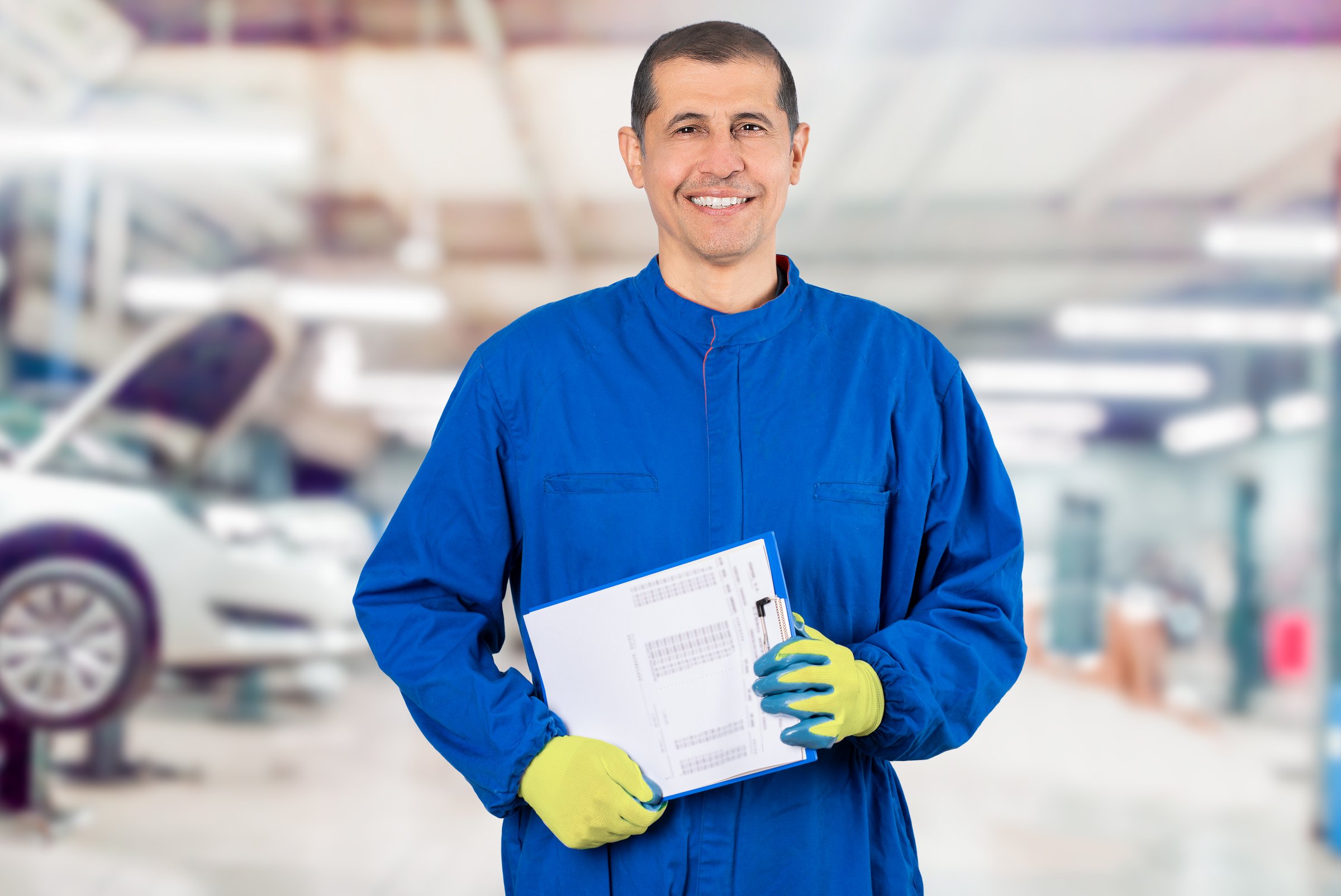 Happy mature mechanic. Portrait of confident mature mechanic in overalls with clipboard at factory