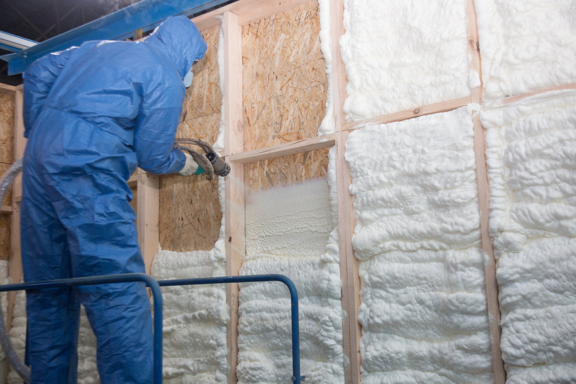 Insulation of walls with foam, energy and heat saving of walls, worker treats walls with foam