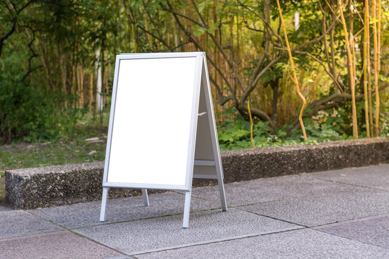 Blank ad space sign infront of trees in a park on the ground