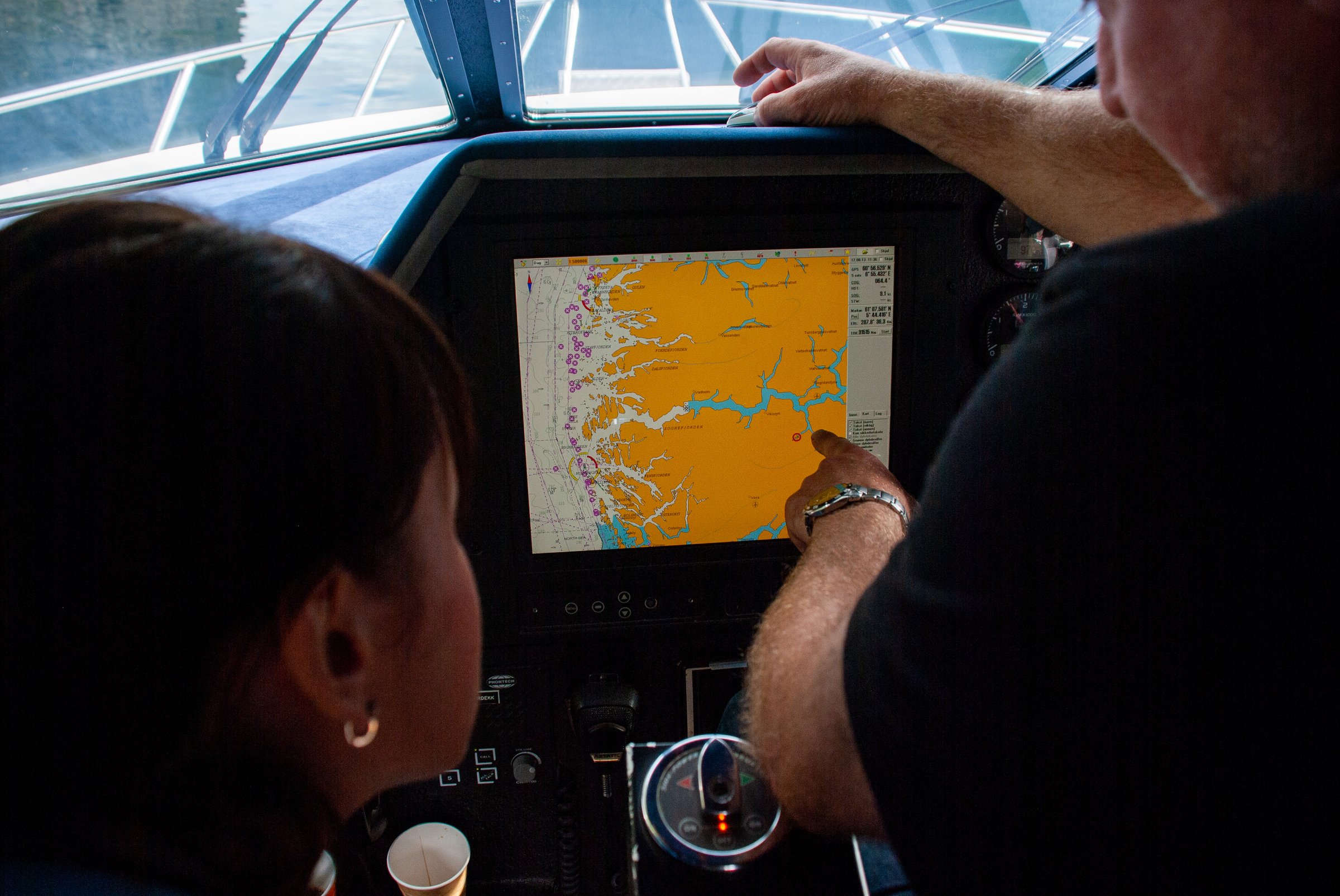 Gudvangen, Norway - August 17, 2013 - Navigation technology on boat with male and female adults examining digital map display.