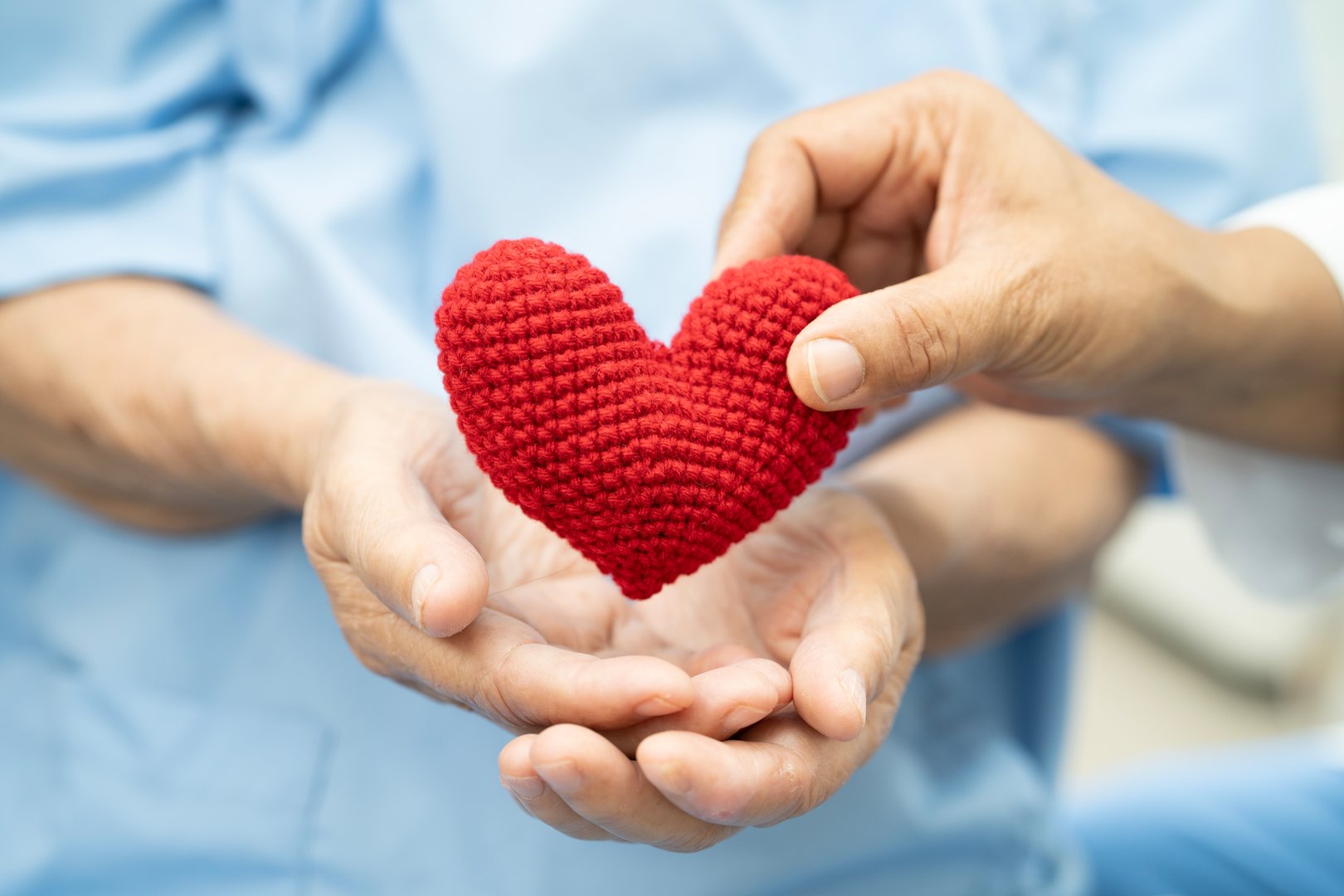 Asian woman patient holding red heart in hand.