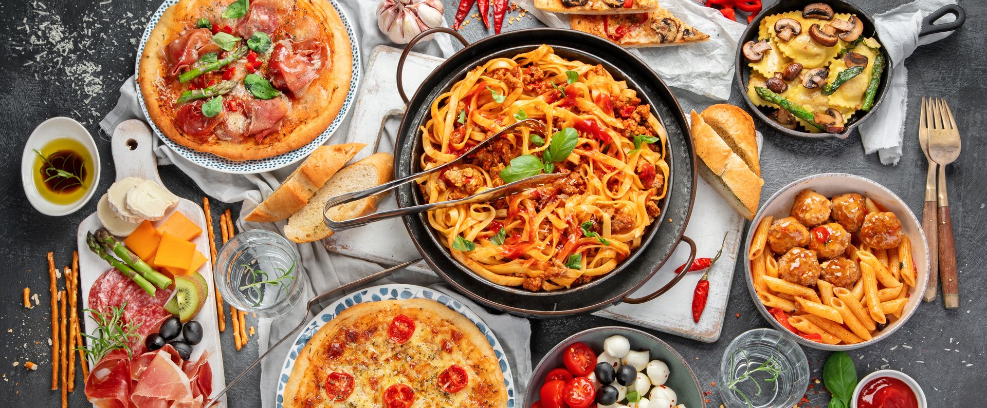 Italian food assortment on dark background. Traditional food concept. Dishes and appetizers. Top view. Panorama.