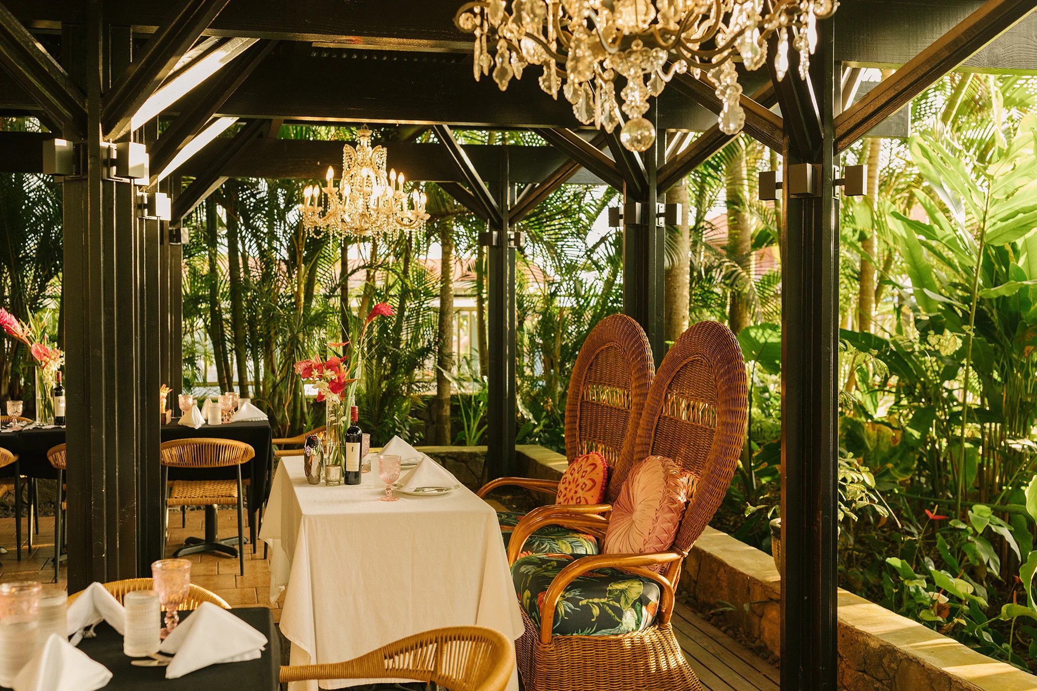 Open-air garden dining at Holualoa Garden & Kitchen with lush tropical foliage and romantic lighting in Holualoa