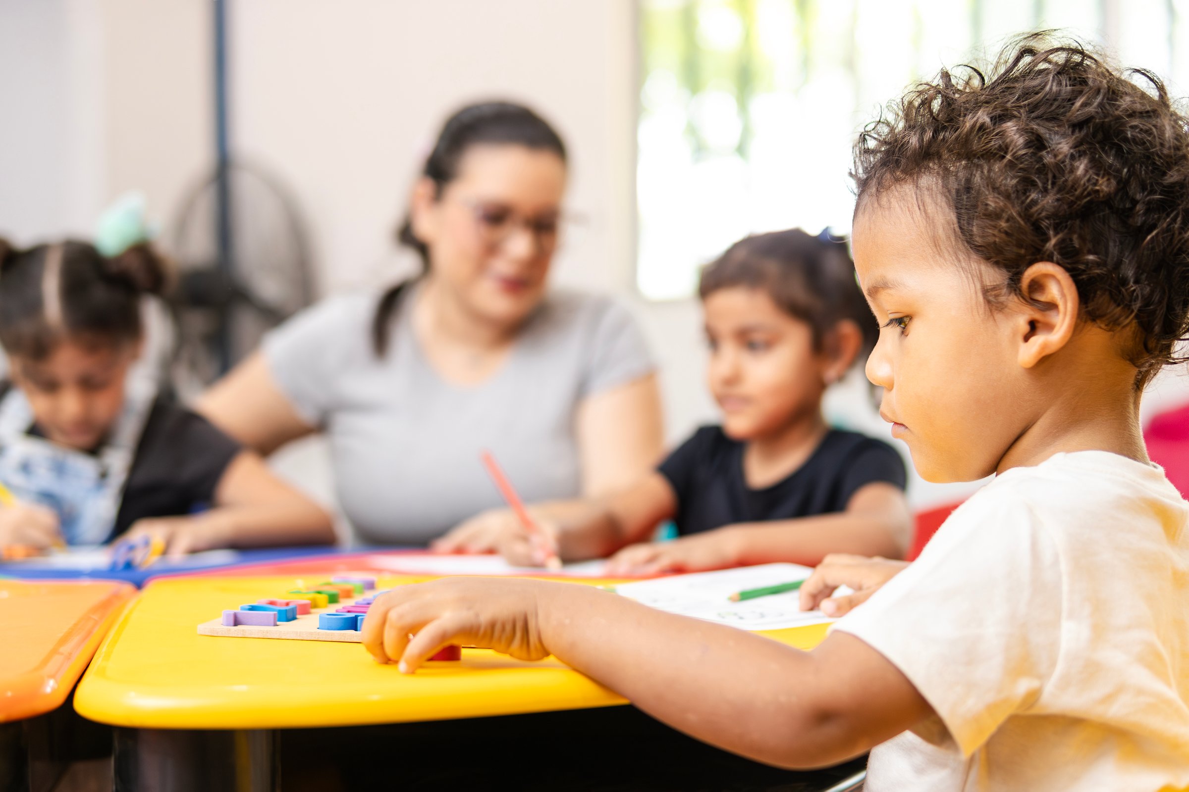 Latin american children learning the alphabet with their teacher in a kindergarten classroom