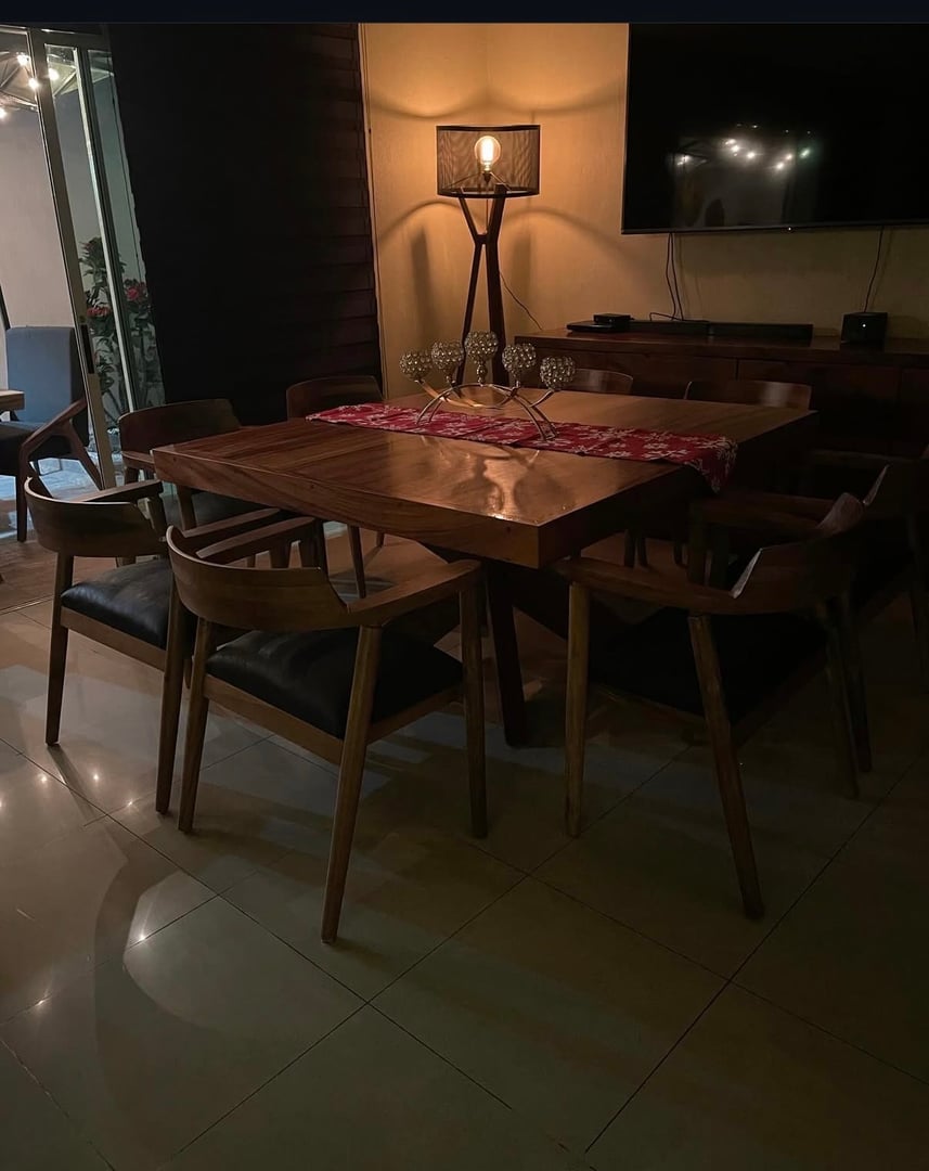 Conjunto de comedor en madera de parota con mesa cuadrada y 8 sillas con respaldo envolvente y asiento tapizado negro