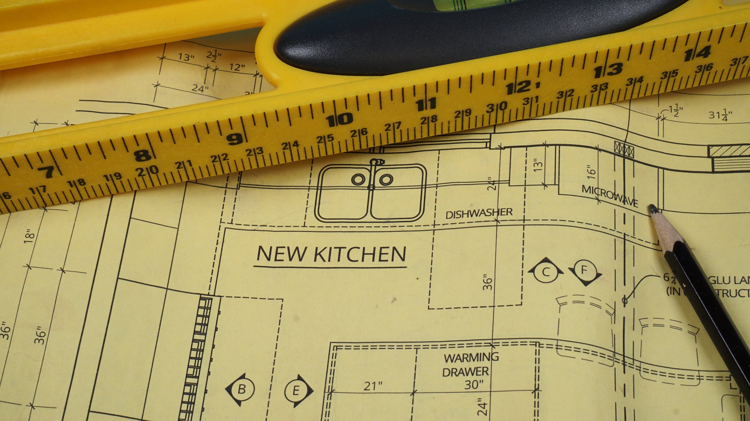 Blueprint plans for a kitchen remodeling project with a ruler level.