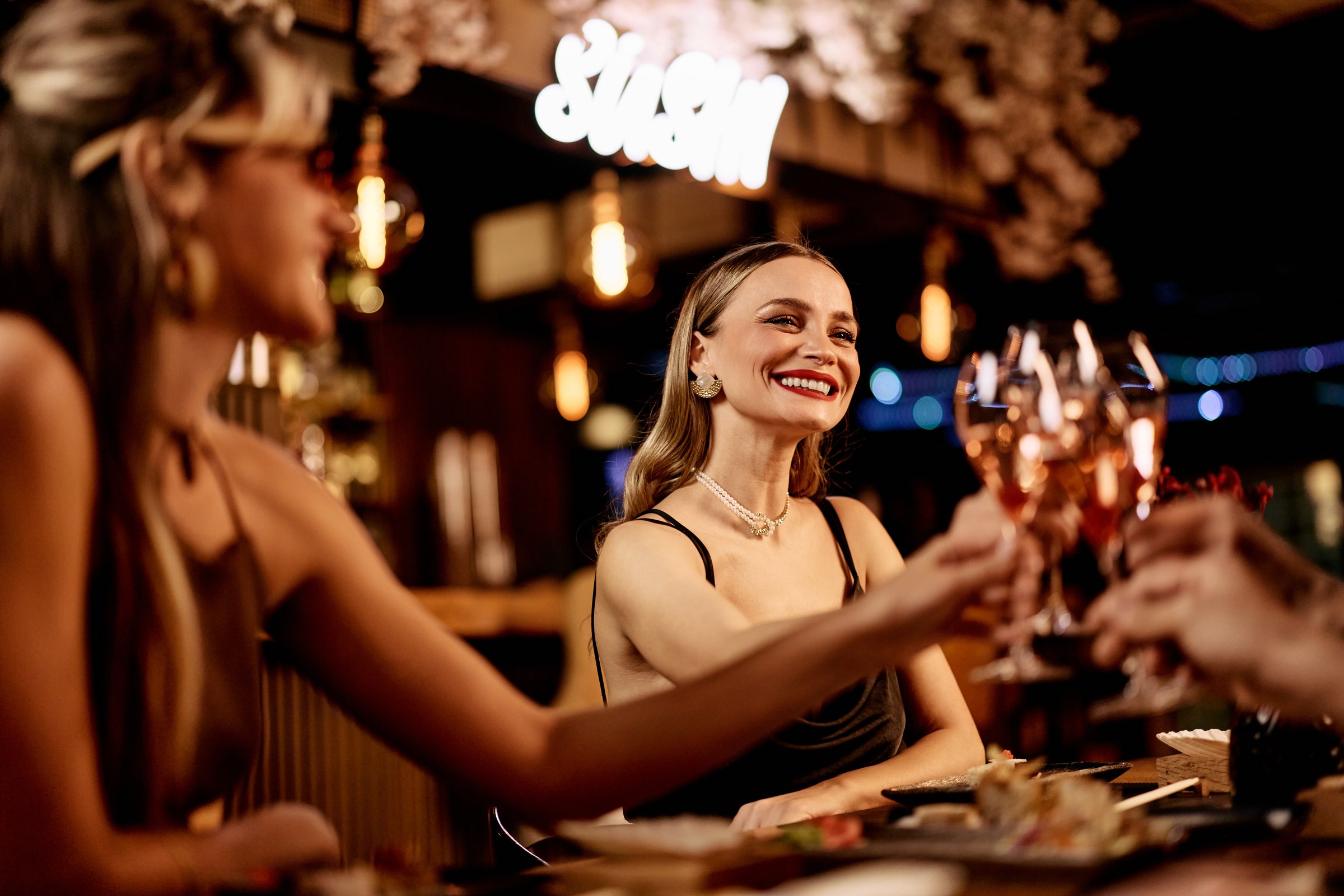 Women enjoying a celebratory toast with drinks in a stylish and vibrant atmosphere.