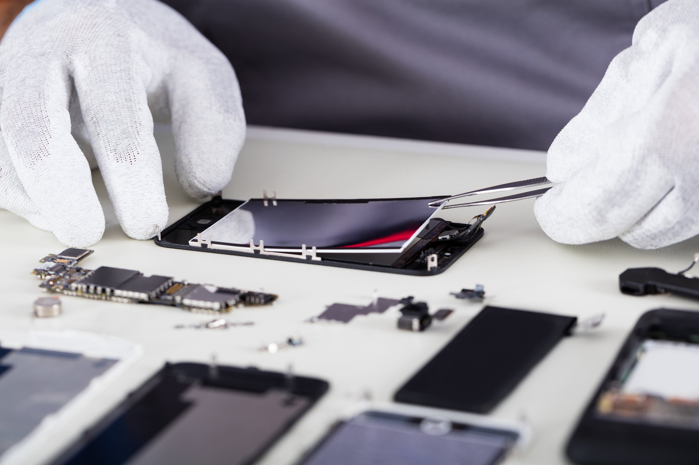 Close-up Of Repairman Disassembling Smartphone With Tweezers