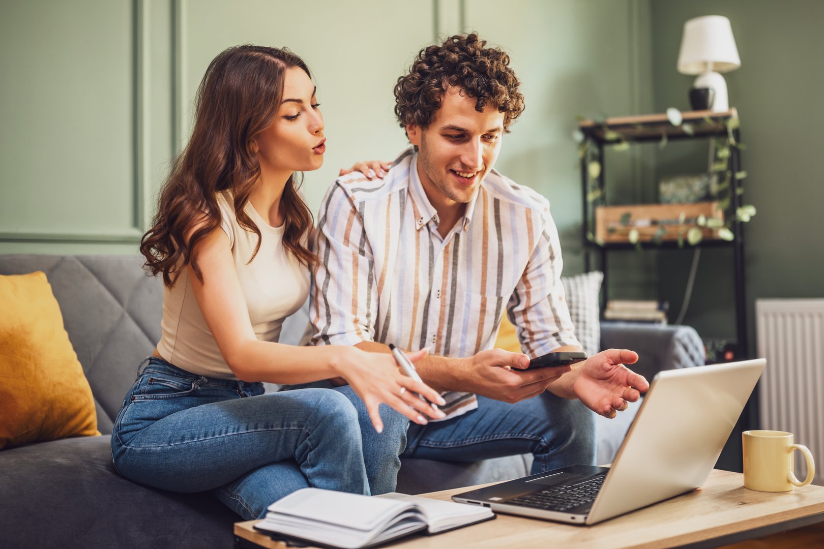 Couple holding financial documents while sitting in a cozy home setting. They discuss investments, savings, and budget while maintaining a positive and collaborative mood.