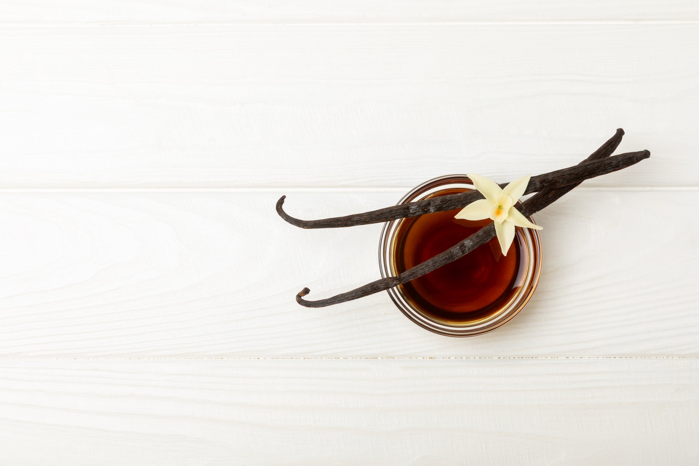 Vanilla extract in glassware on  table. Vanilla extract for baking and desserts. Aromatic Homemade Vanilla Extract. Close -up. Place for the text. Copy space.