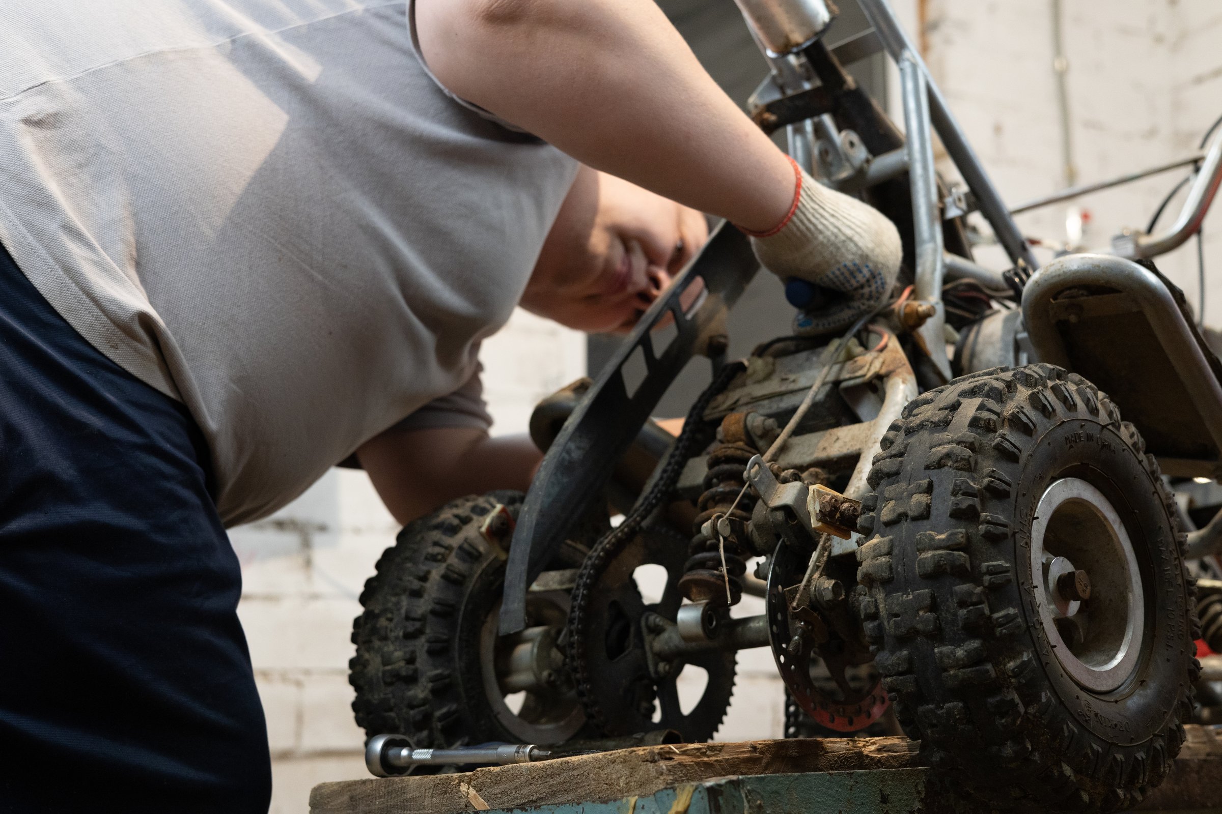 Installing a new part on an ATV to replace a broken old one. Do-it-yourself repair of a children's ATV in the garage for a child. A father is repairing his son's ATV in the garage..