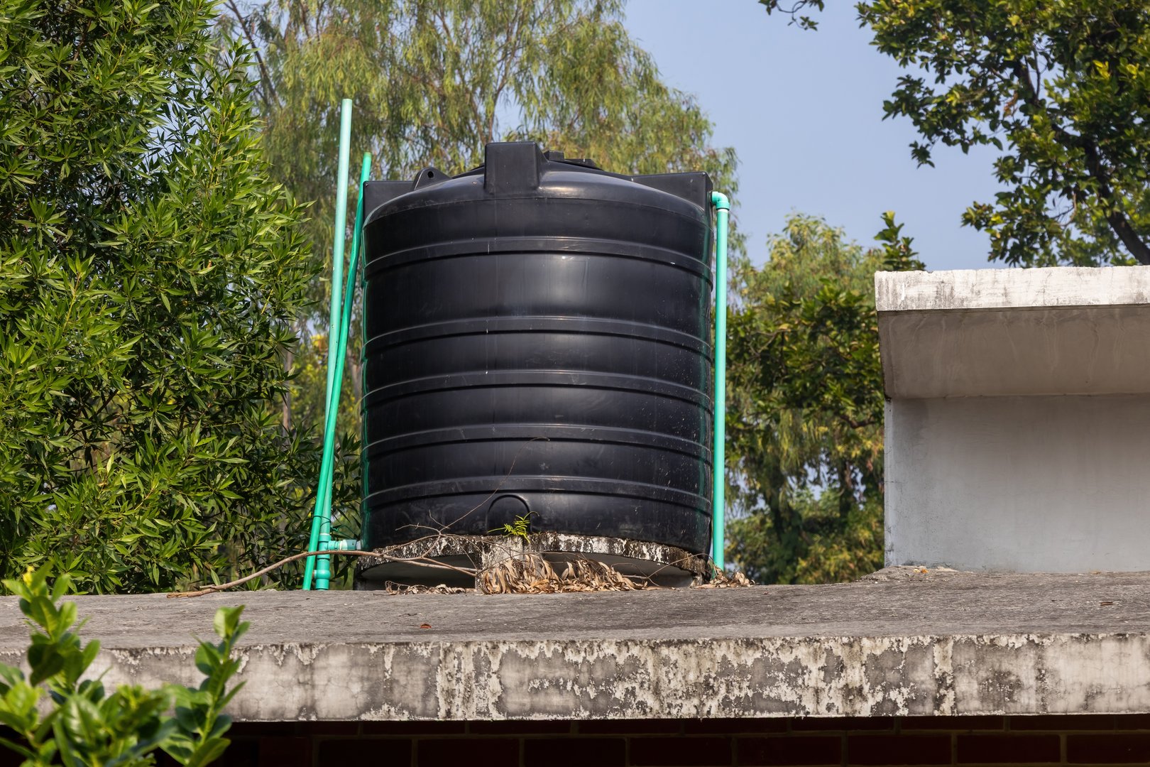 A large black plastic water storage tank (container) installed on a building rooftop, used for reserving and supplying water for domestic, industrial, or drinking purposes in an urban setting.