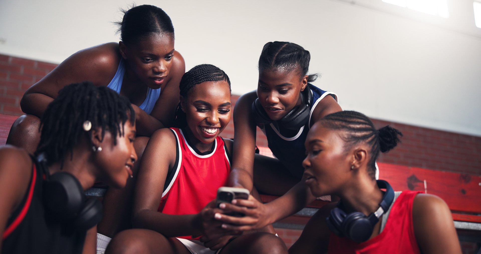 Sports, athlete and group with mobile, break and promotion for game on social media, smile and online. Basketball player, team and black women with smartphone for post, fitness and browsing on web
