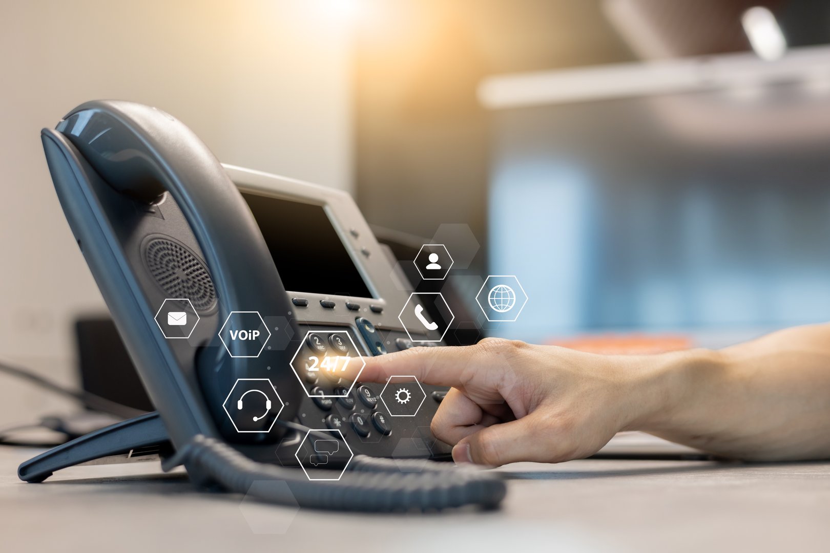 close up employee call center man hand point and press button number telephone voip machine in the office desk with virtual icon of communication technology for business and contact us concept