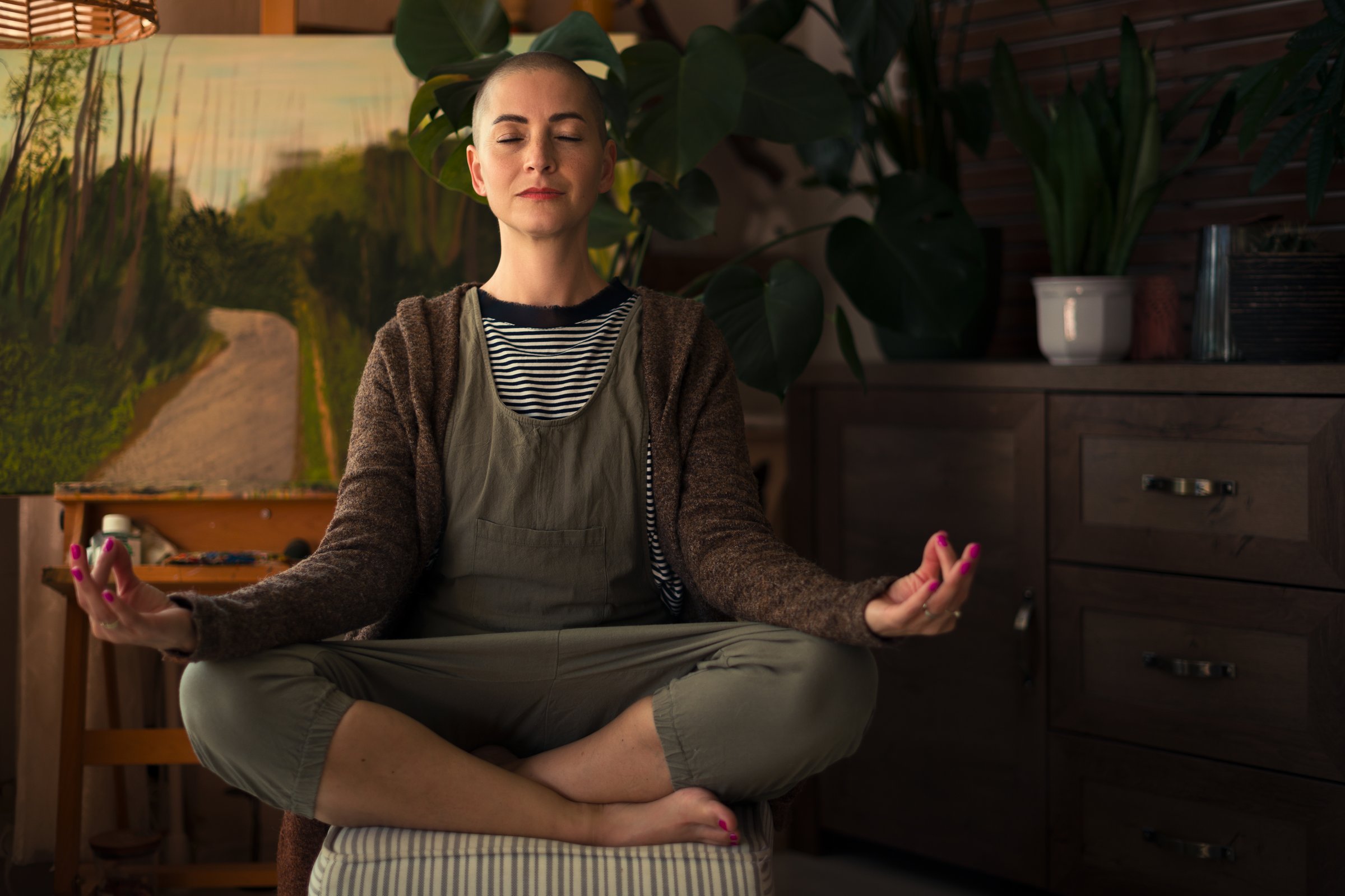 Young female cancer patient meditating in livingroom. Mental health, life balance, mindfulness and meditation concept.