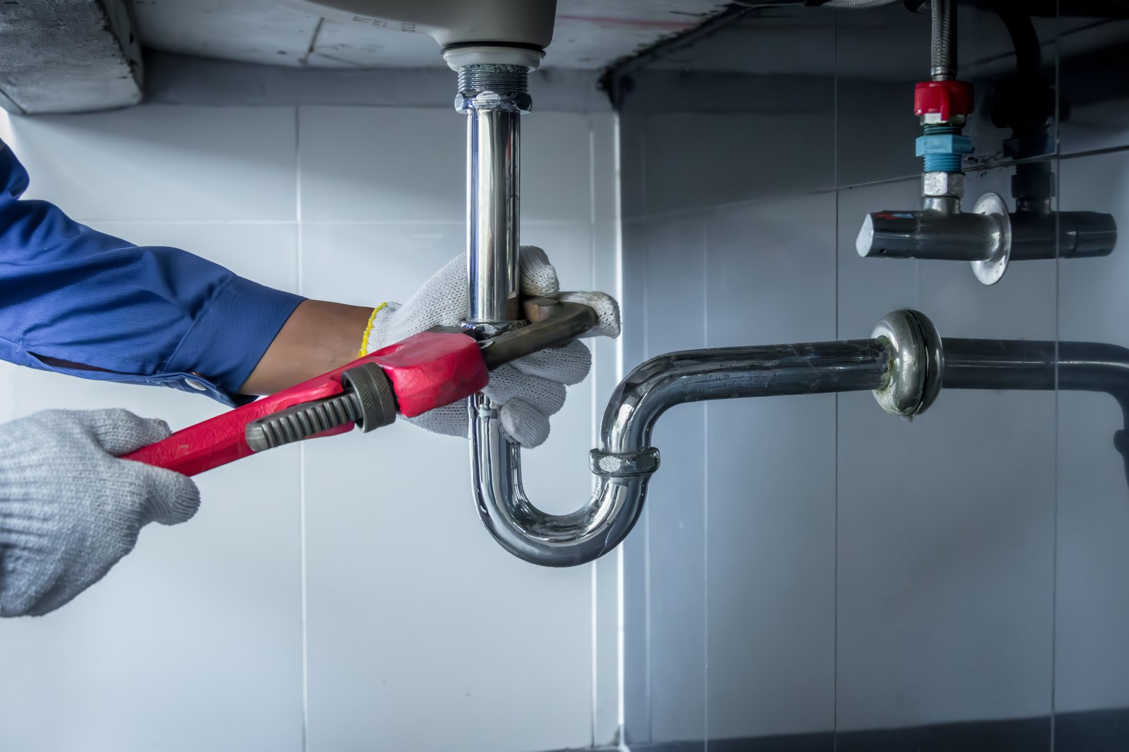 Plumber hands holding wrench doing repairing work at the sink and clogged pipe in bathroom carefully