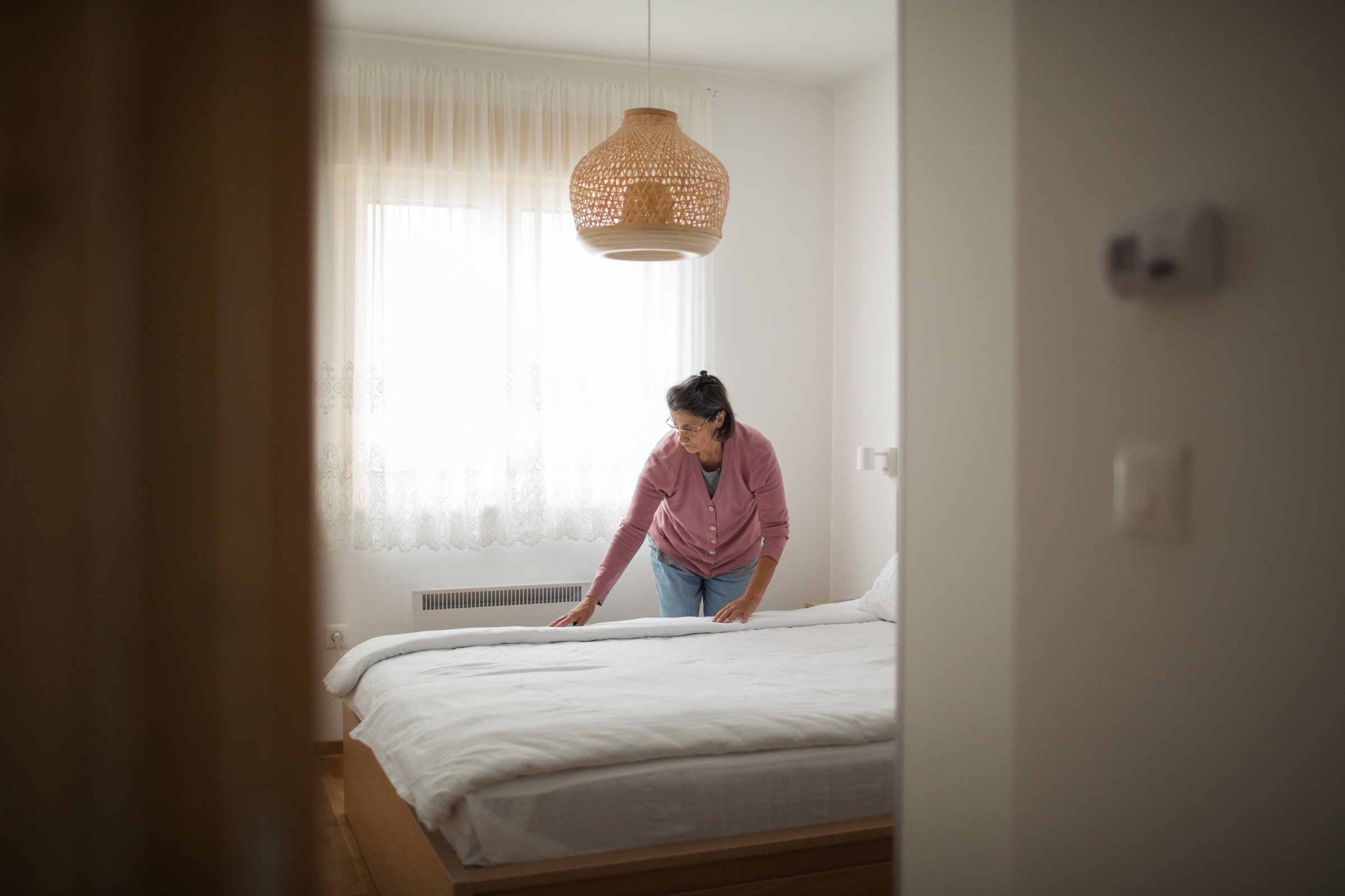 Elderly woman prepares the bed for her next guest.