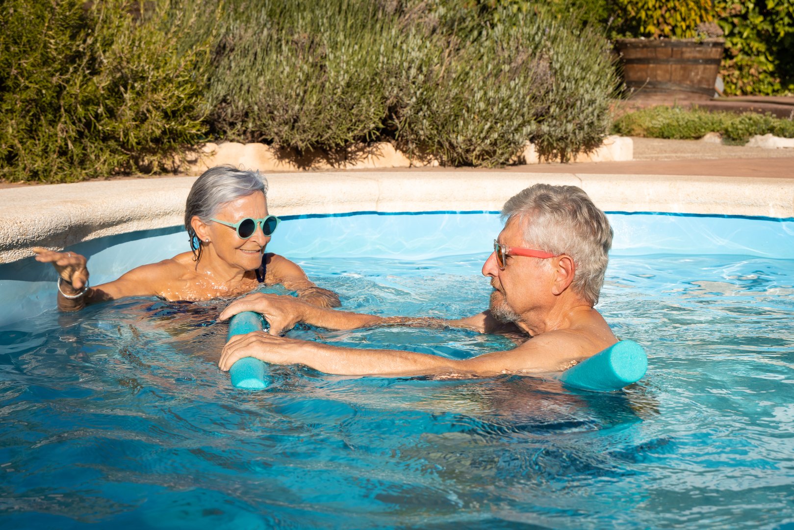 Happy elderly couple enjoying a fun and refreshing workout with foam noodles