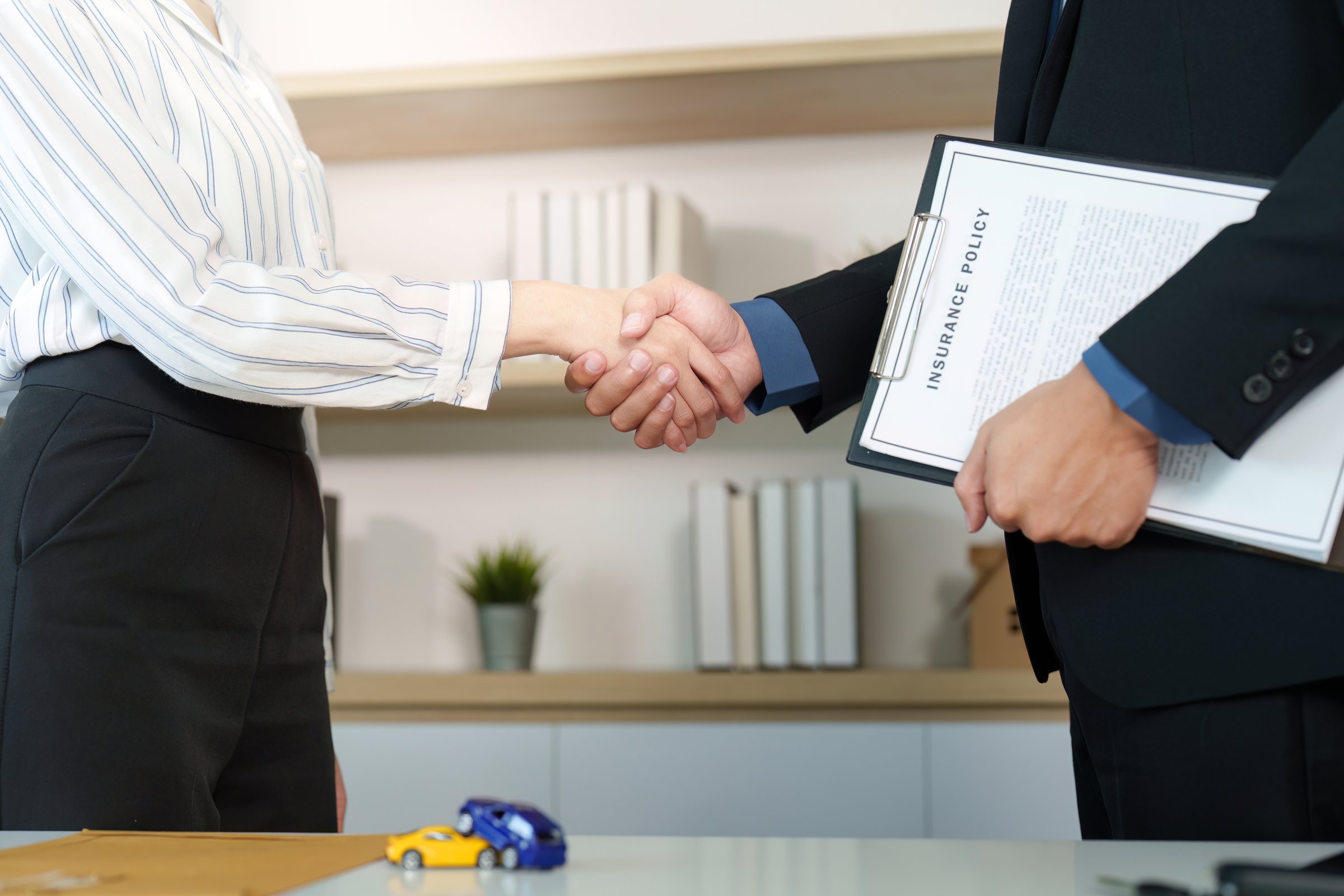A client and insurance agent shake hands after finalizing an agreement, showcasing trust and professionalism.