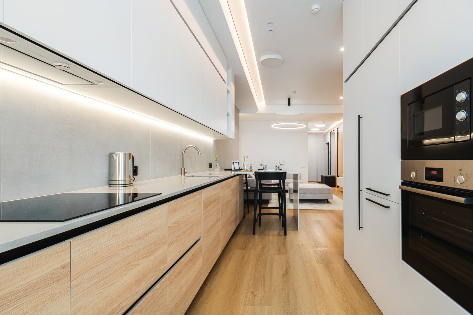 A stylish kitchen showcases light wood cabinetry, a sleek countertop, and modern appliances. Natural light highlights the minimalist design, creating a serene cooking area.