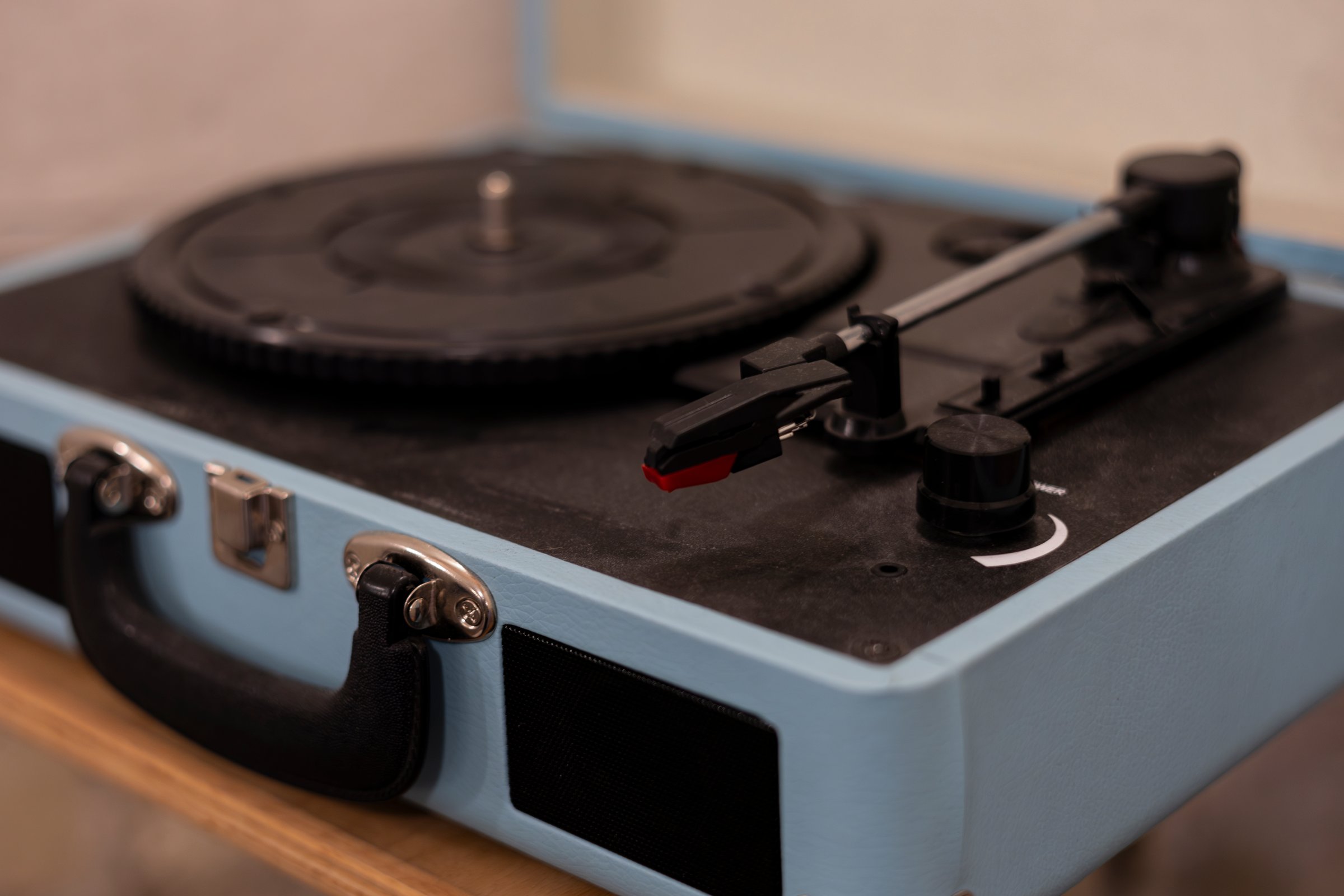 Close up of a blue vintage record player sitting on a table in a music studio. Record player without vinyl disk. Retro equipment for playing music. Blue vinyl record player without a record.