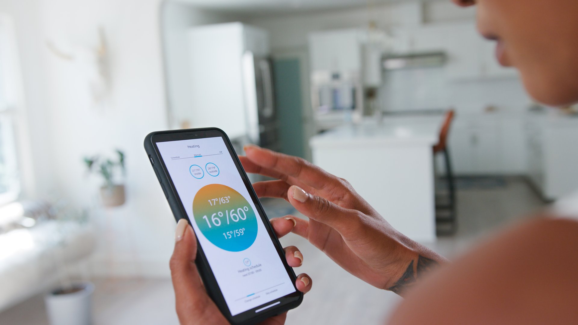 Close Up Of Woman Controlling House Central Heating Temperature Using App On Mobile Phone