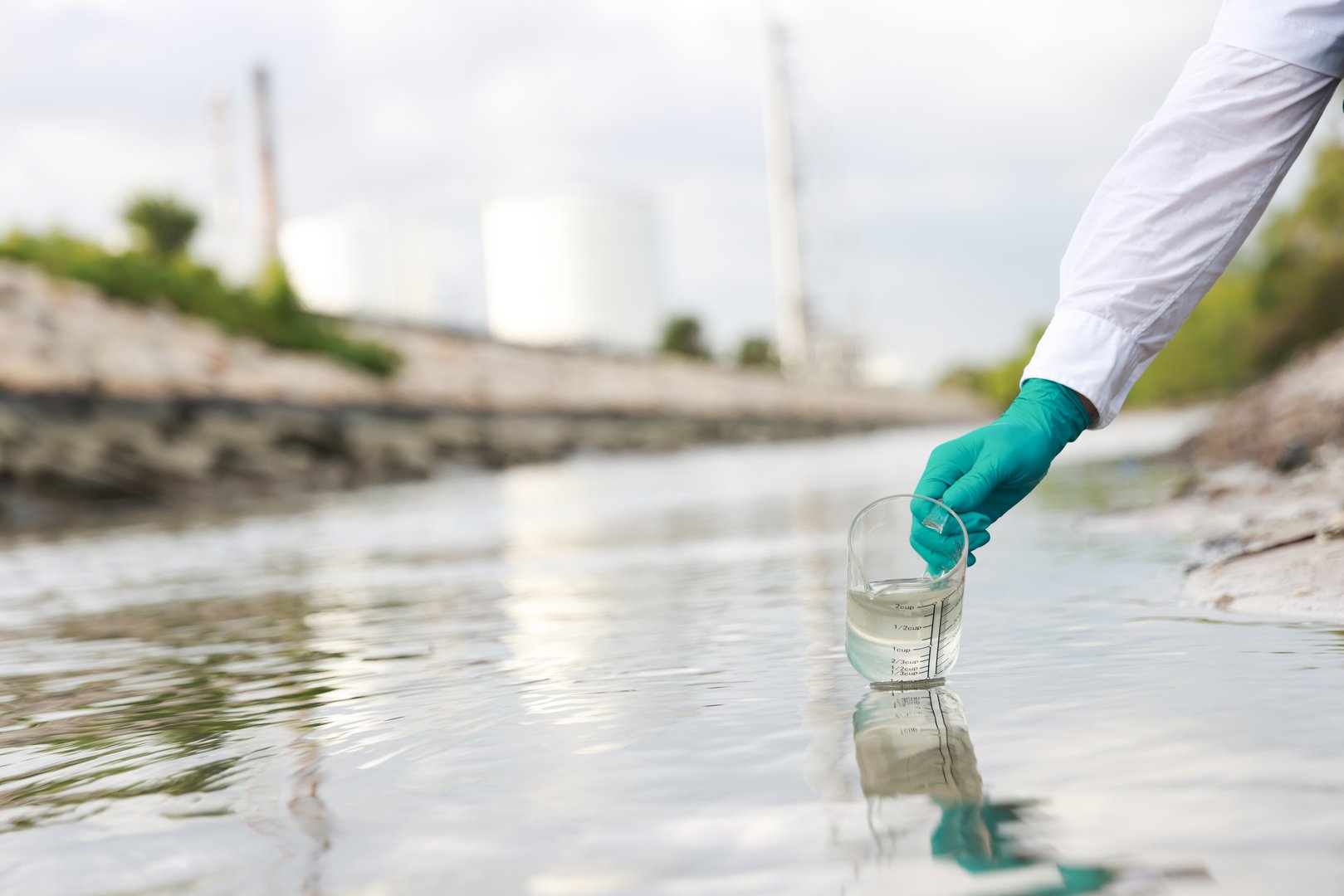 Environmental engineers taking water samples near factory