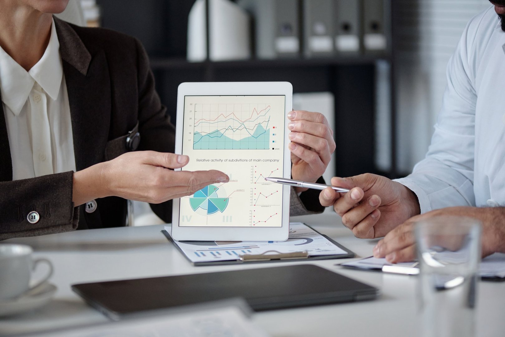 Close up of unrecognizable woman pointing at statistics graph on tablet screen while sitting at meeting table in medical conference copy space