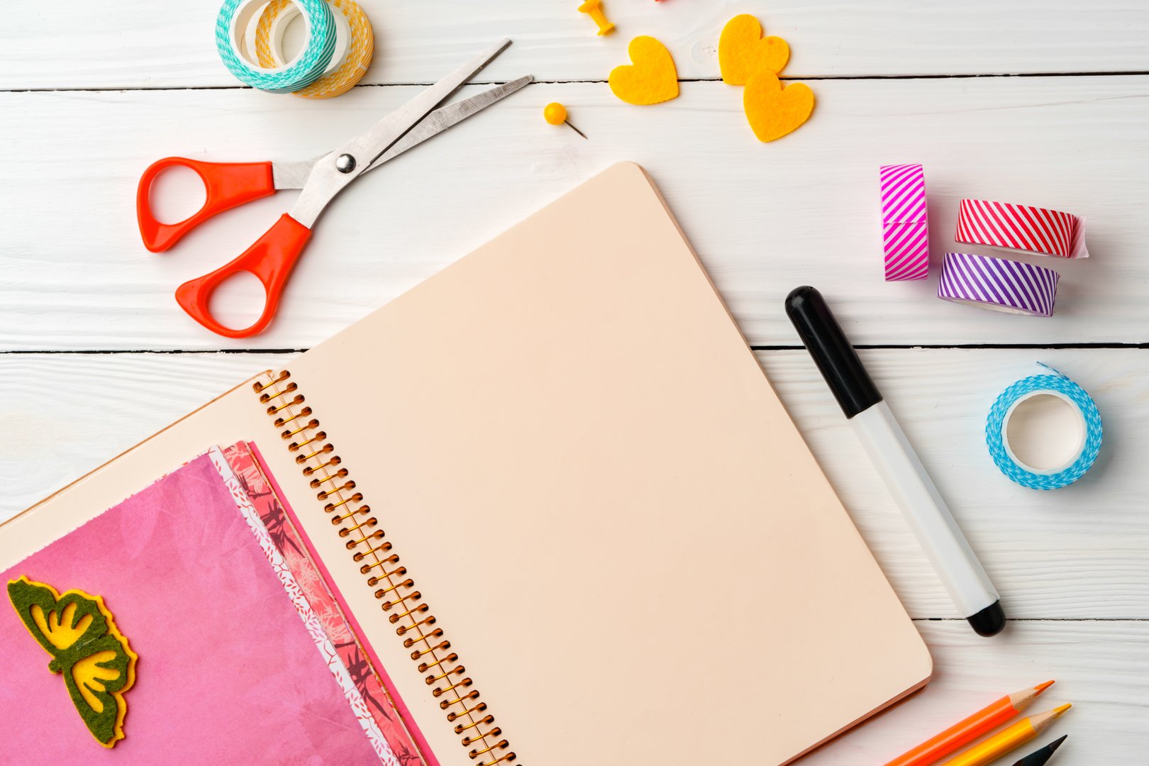 Creative workspace with open notebook, stationery, and decorative items on a wooden table copy space