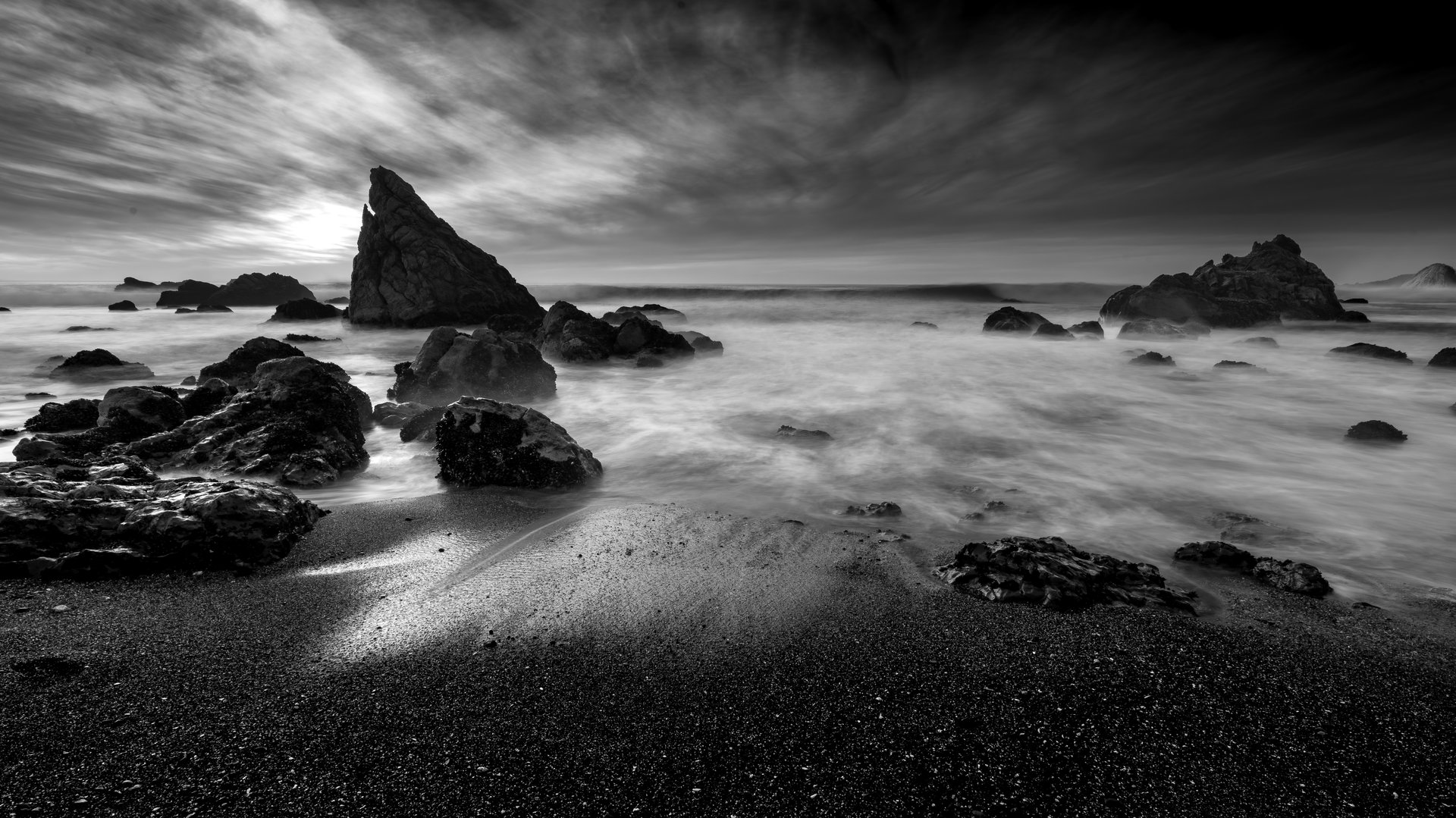 Streaking water coastline with rocky ocean and dark seas in background cold and winter.