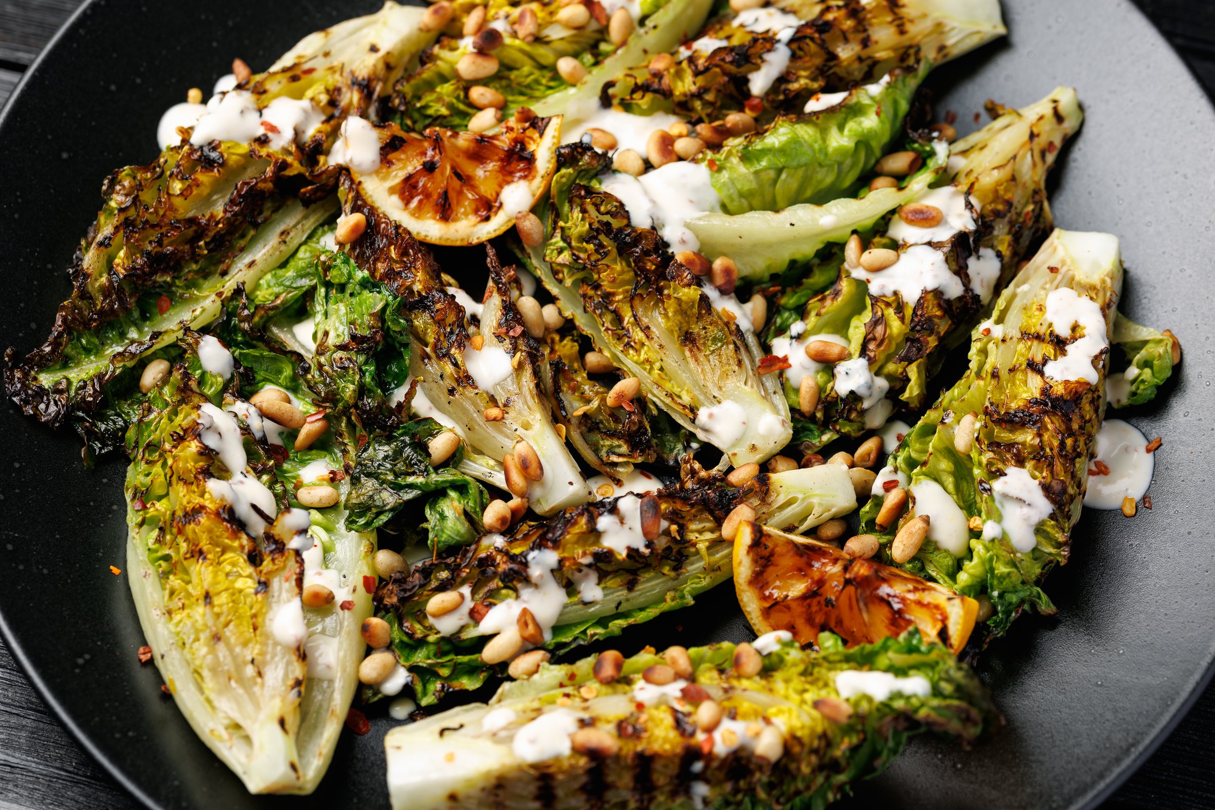Grilled little gem lettuce with aioli sauce, roasted pine nuts and chilli flakes. Healthy Low carb side salad.