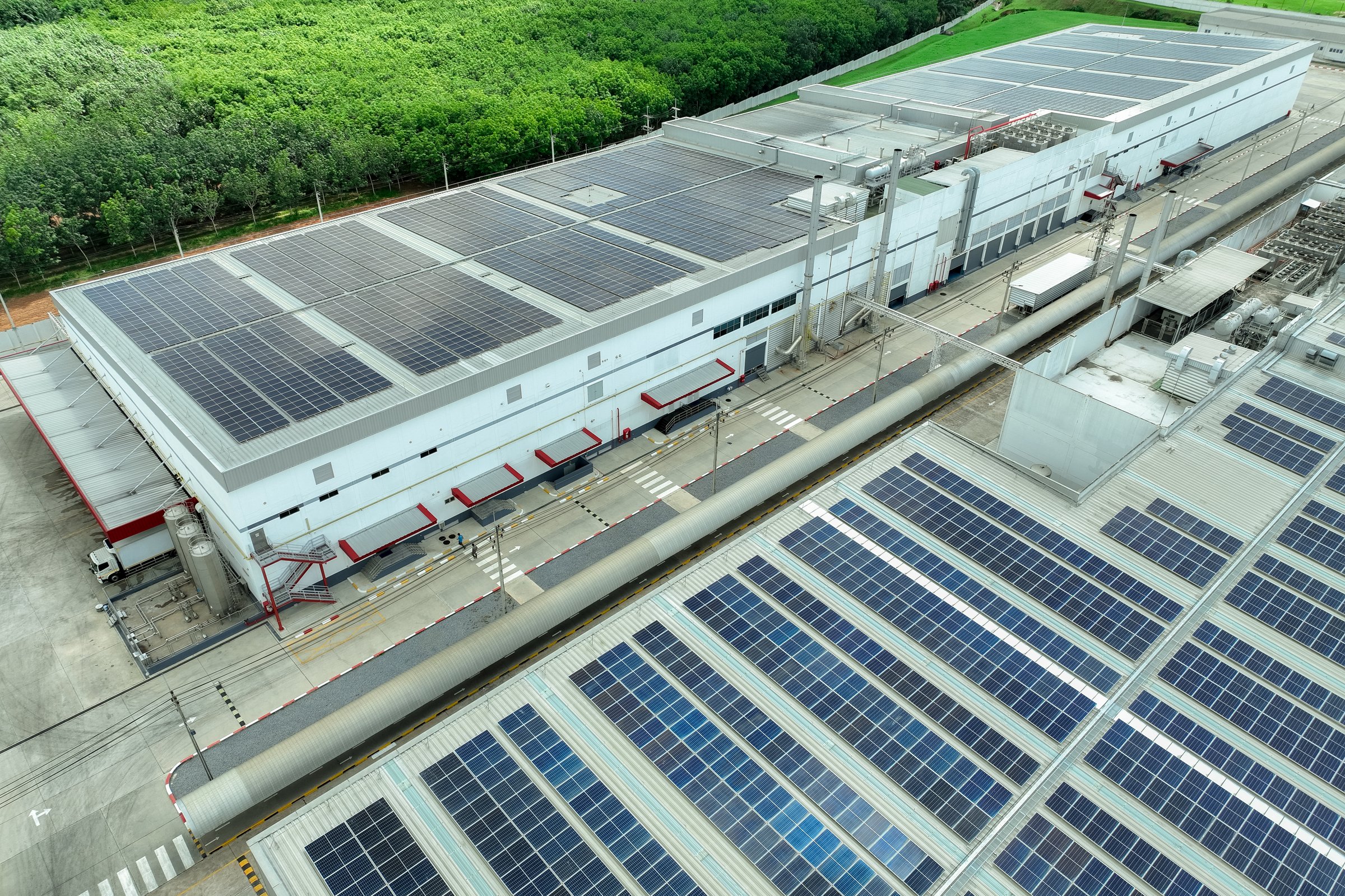 Solar energy for factory and warehouse building. Solar panels on roof of industrial plant. Commercial solar power. Rooftop solar power. Rooftop renewable energy system. Sustainable green energy.