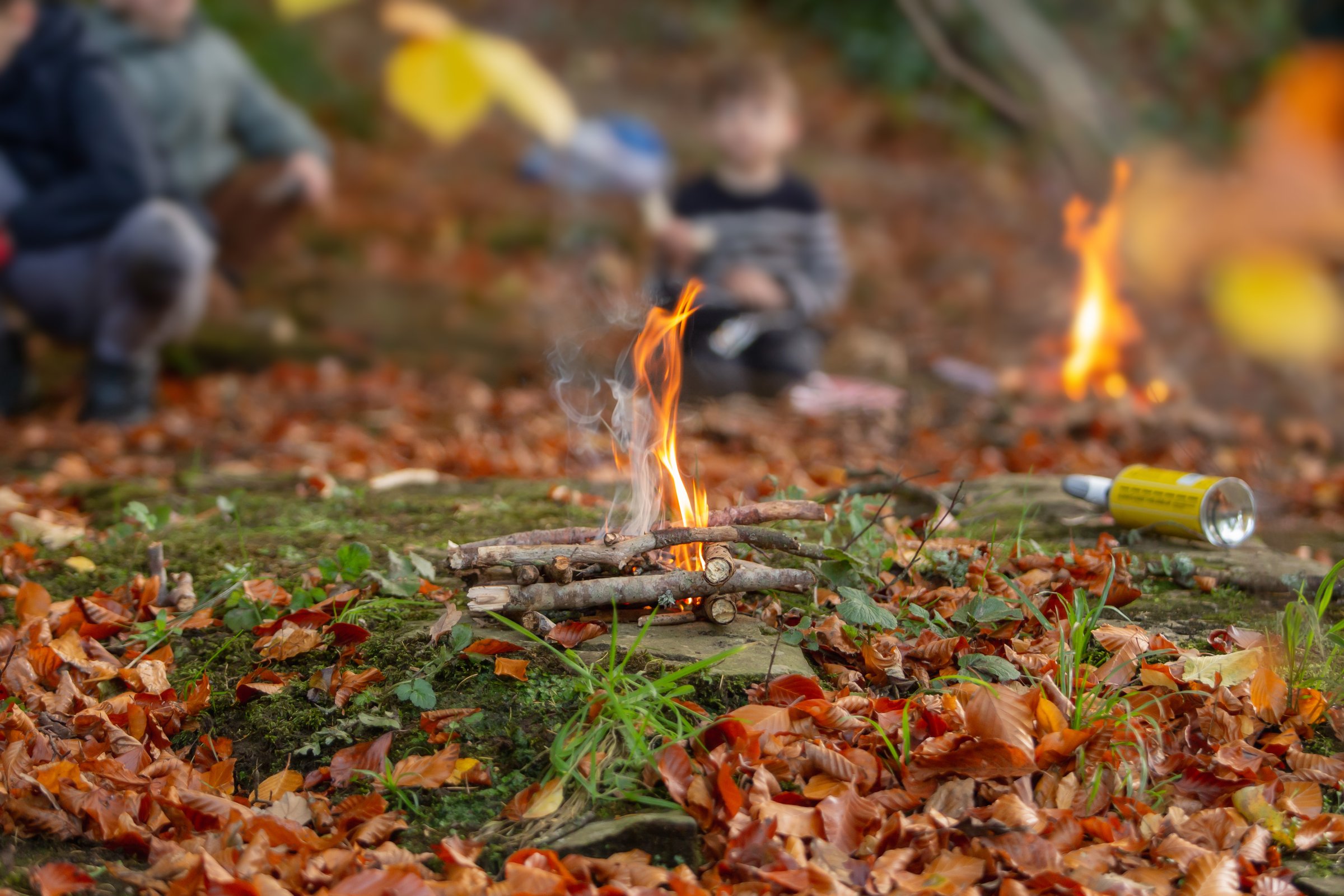 Boy sitting behind campfire, blurred camping adventure concept