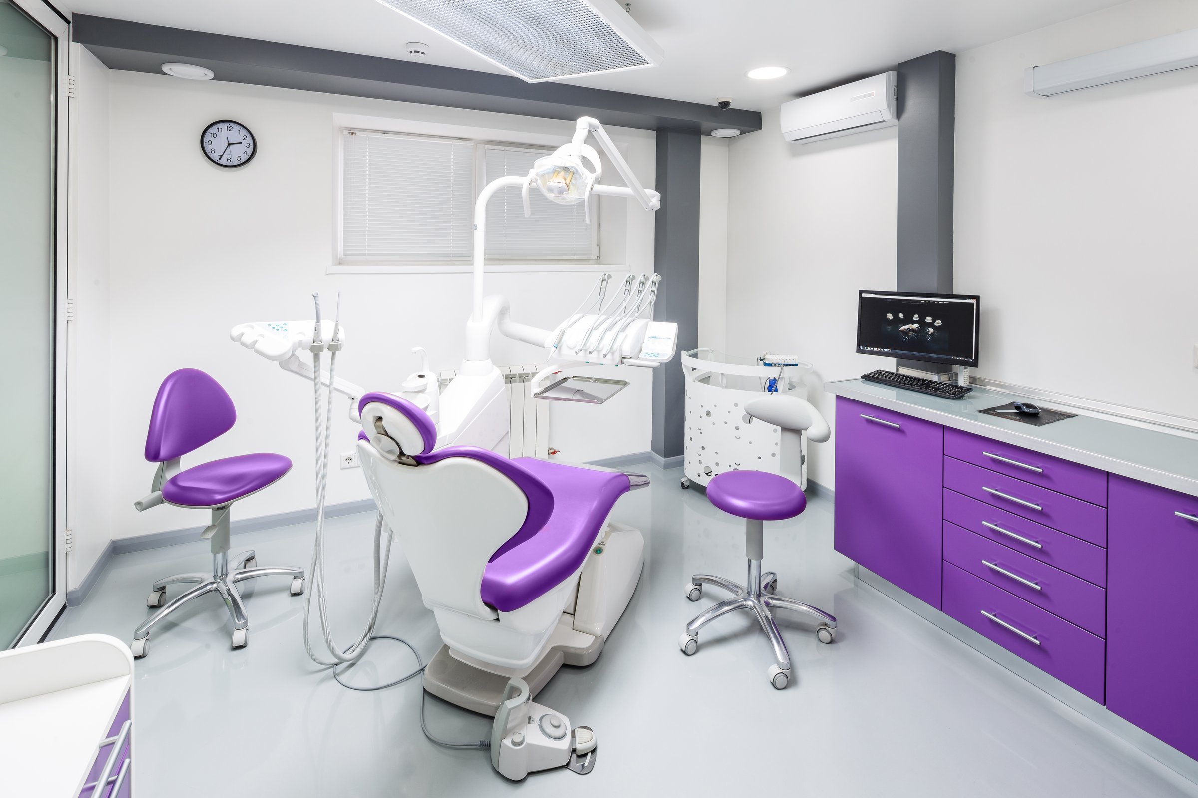 This image showcases a modern dental office equipped with purple chairs, advanced dental tools, and a clean, bright workspace that reflects a professional and welcoming environment.