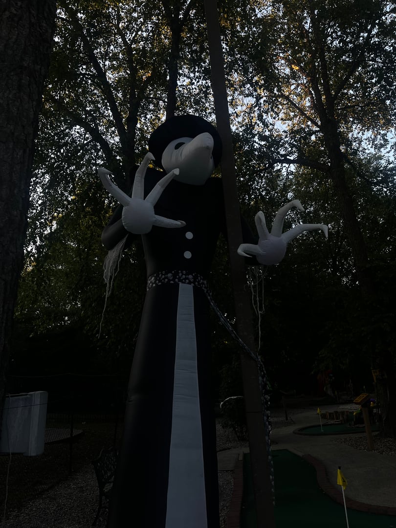 Dark and mysterious Halloween mini golf scene with shadowy decorations