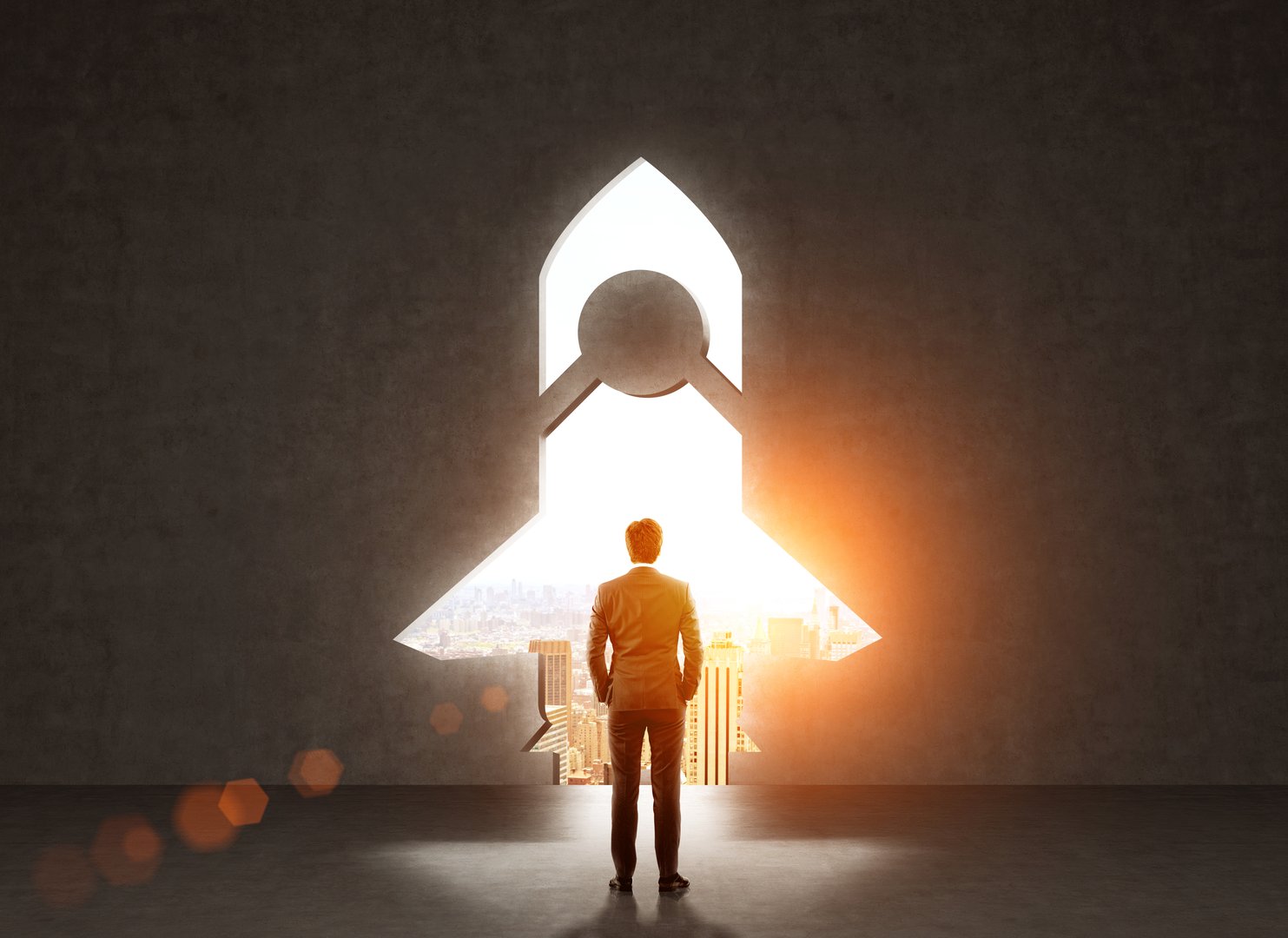 Start up concept with businessman standing in front of rocket shaped gap in wall, revealing sunlit New York city view